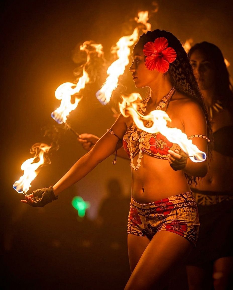 Fire performer twirls flaming batons in a mesmerizing dance display against dark background.
