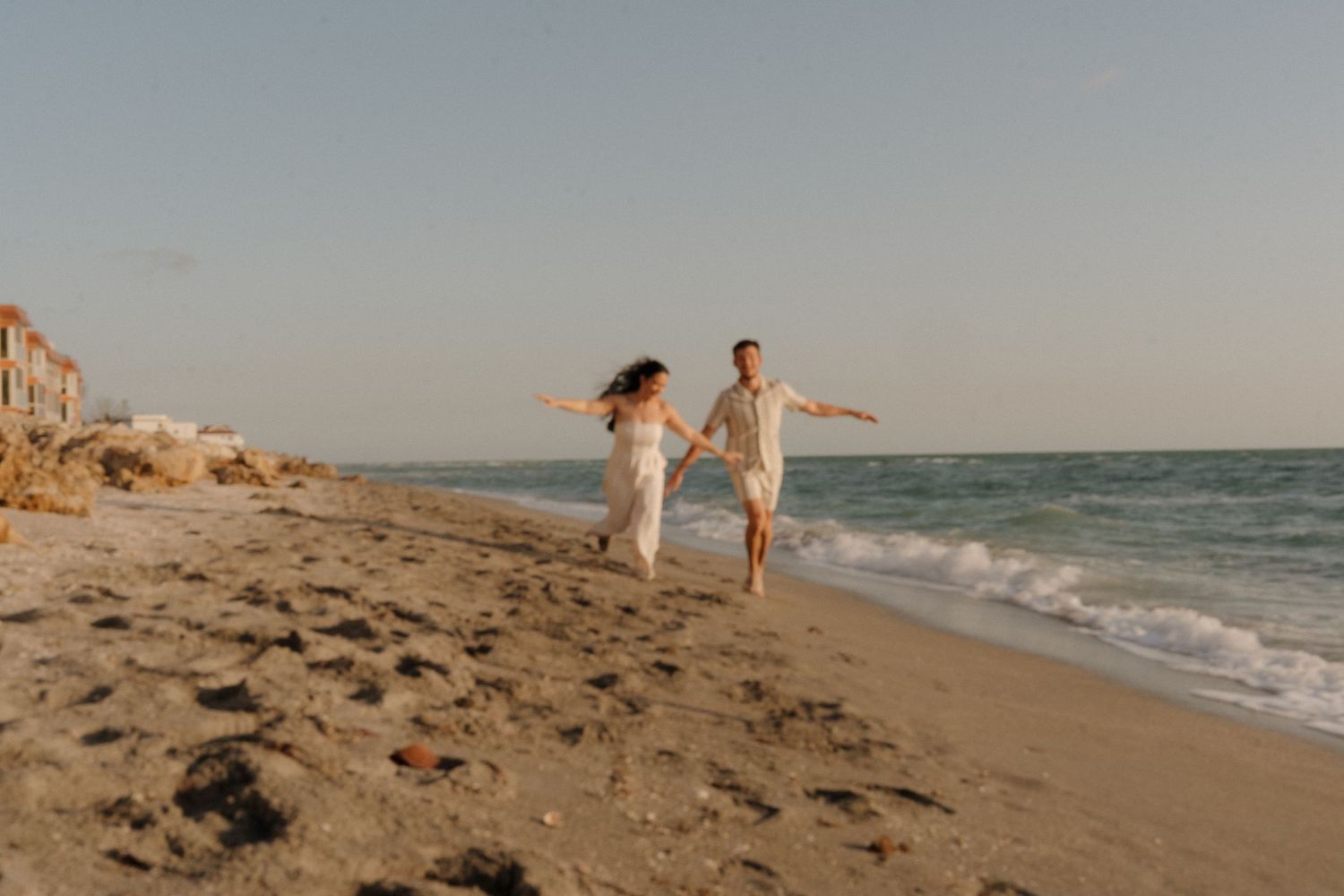 Family playing and running along a sandy beach at sunset.