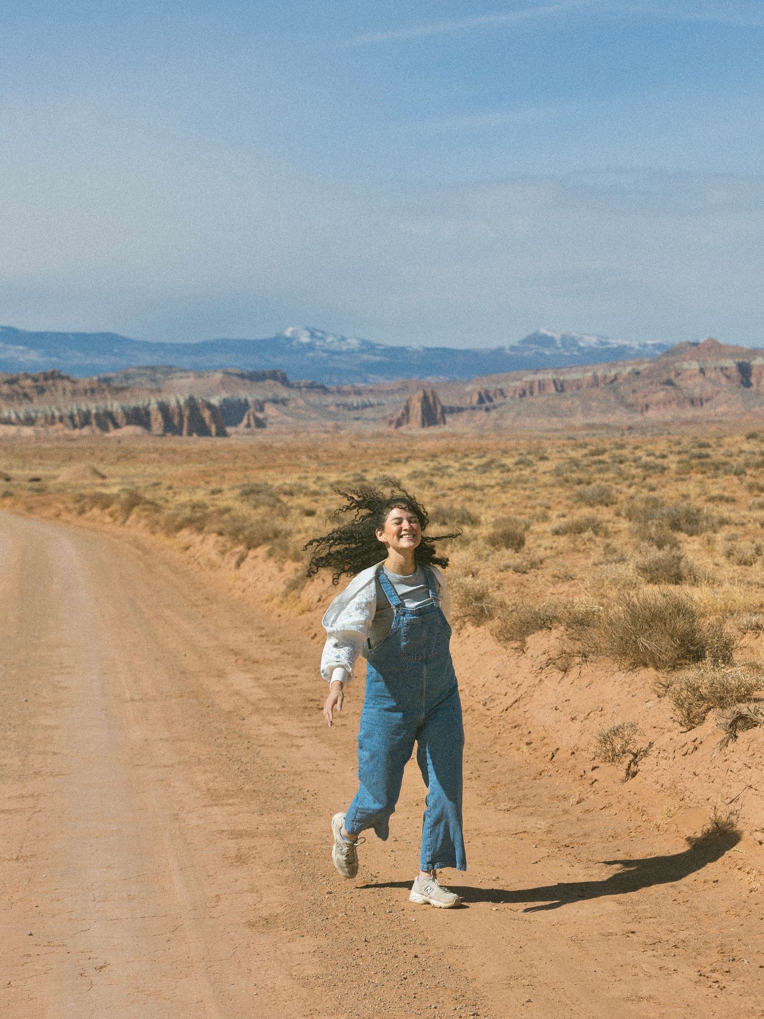 Fun poses on desert trail with mountains and clear blue sky in background.