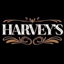 White Harvey's logo with brown ornamental design elements on black background. food photographer photography videographer videography
