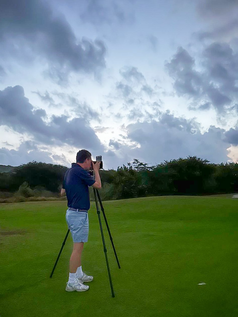 Peter van Weel taking pictures at sunset on a golf course with dramatic cloudy sky in the background.