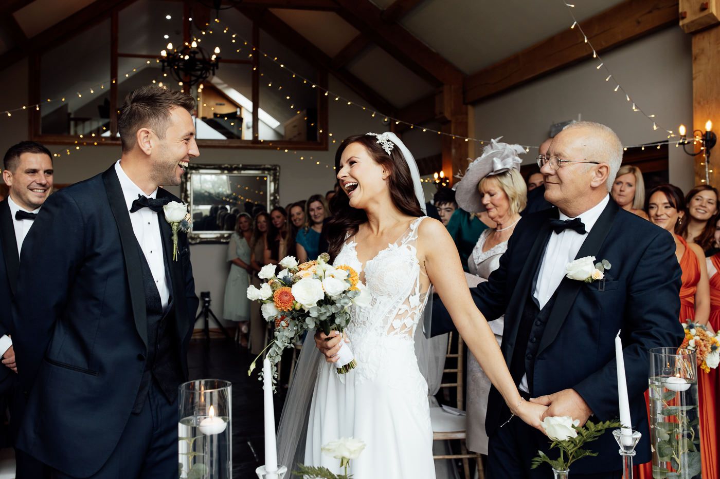 A joyous wedding celebration inside a rustic barn venue decorated with twinkling lights and filled with happy guests.