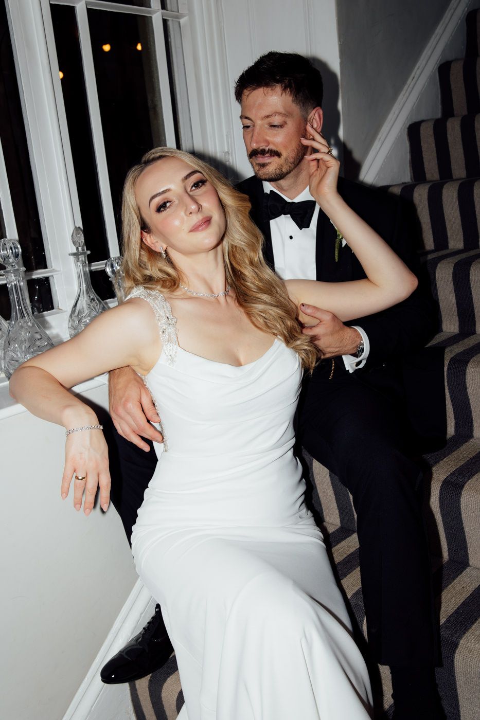 A couple dances energetically at a wedding reception as the bride twirls in her white dress beneath elegant lighting.