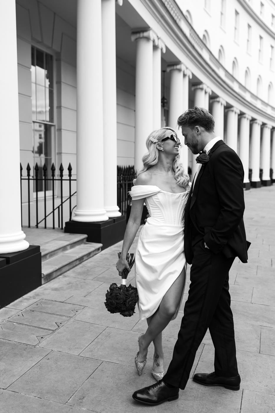 A sequence of black and white photos showing a couple walking along a colonnade with white pillars and iron railings.