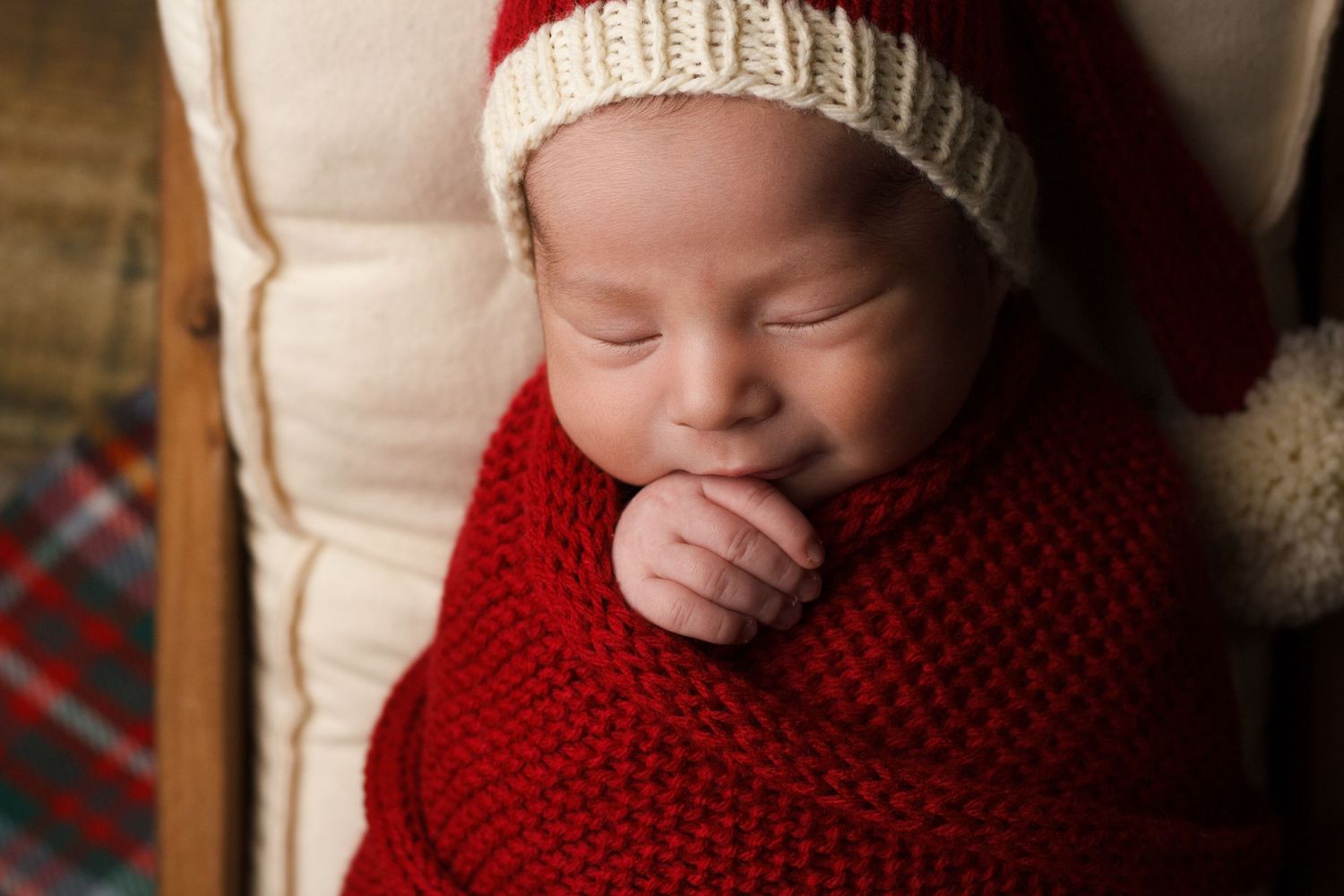 Newborn baby wrapped in deep red knit with a cream hat during a styled newborn photography session in Dalton, Georgia.