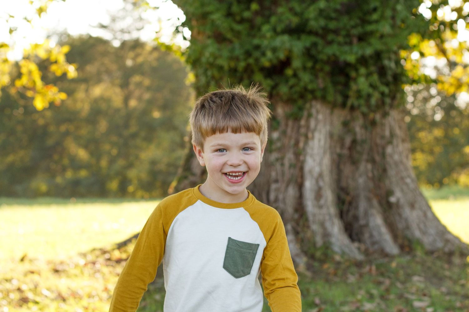 Young boy smiling in mustard and green shirt during golden hour session – North Georgia children’s photography