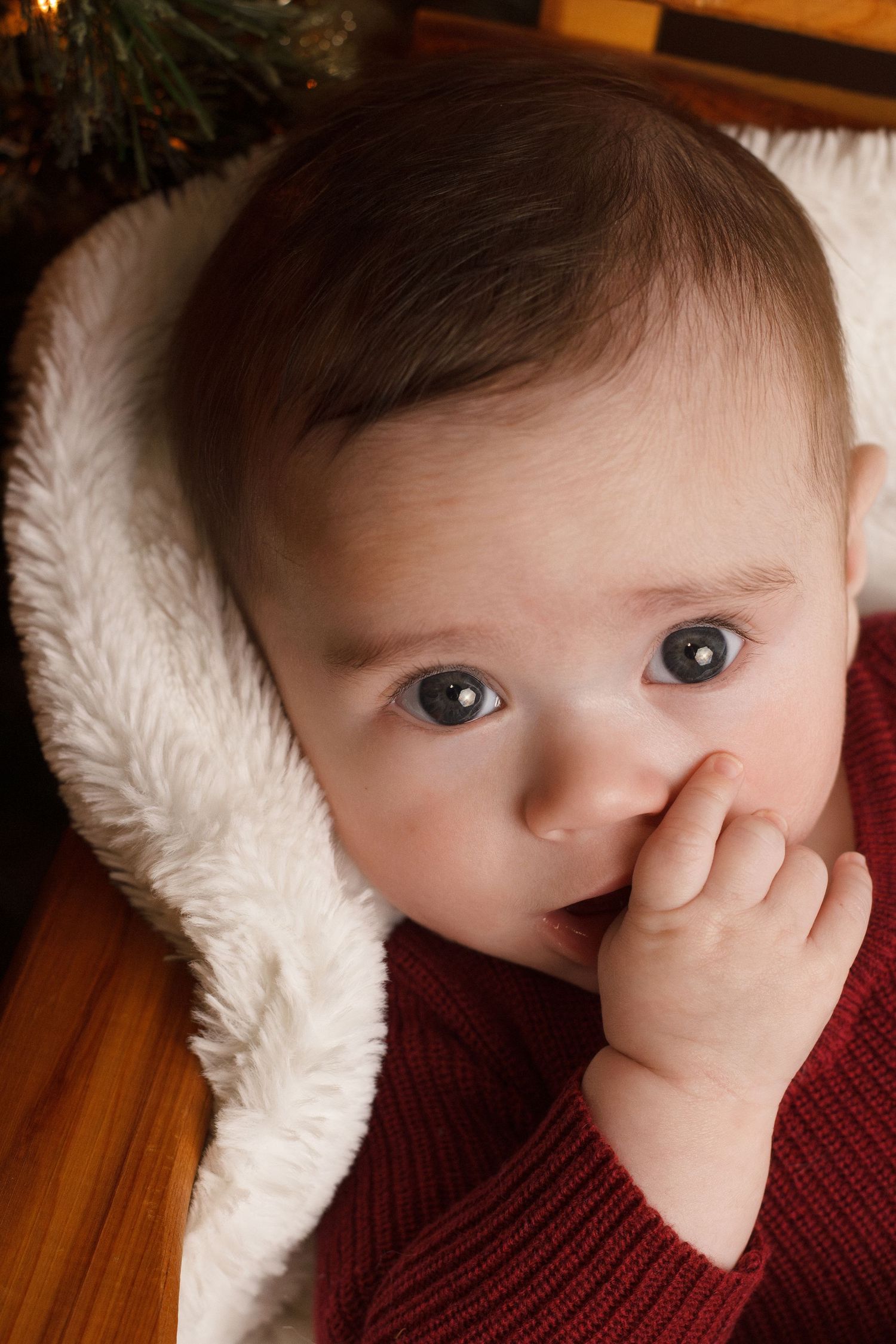 Baby boy  in red sucking on fingers during an in home milestone session in Ringgold Georgia