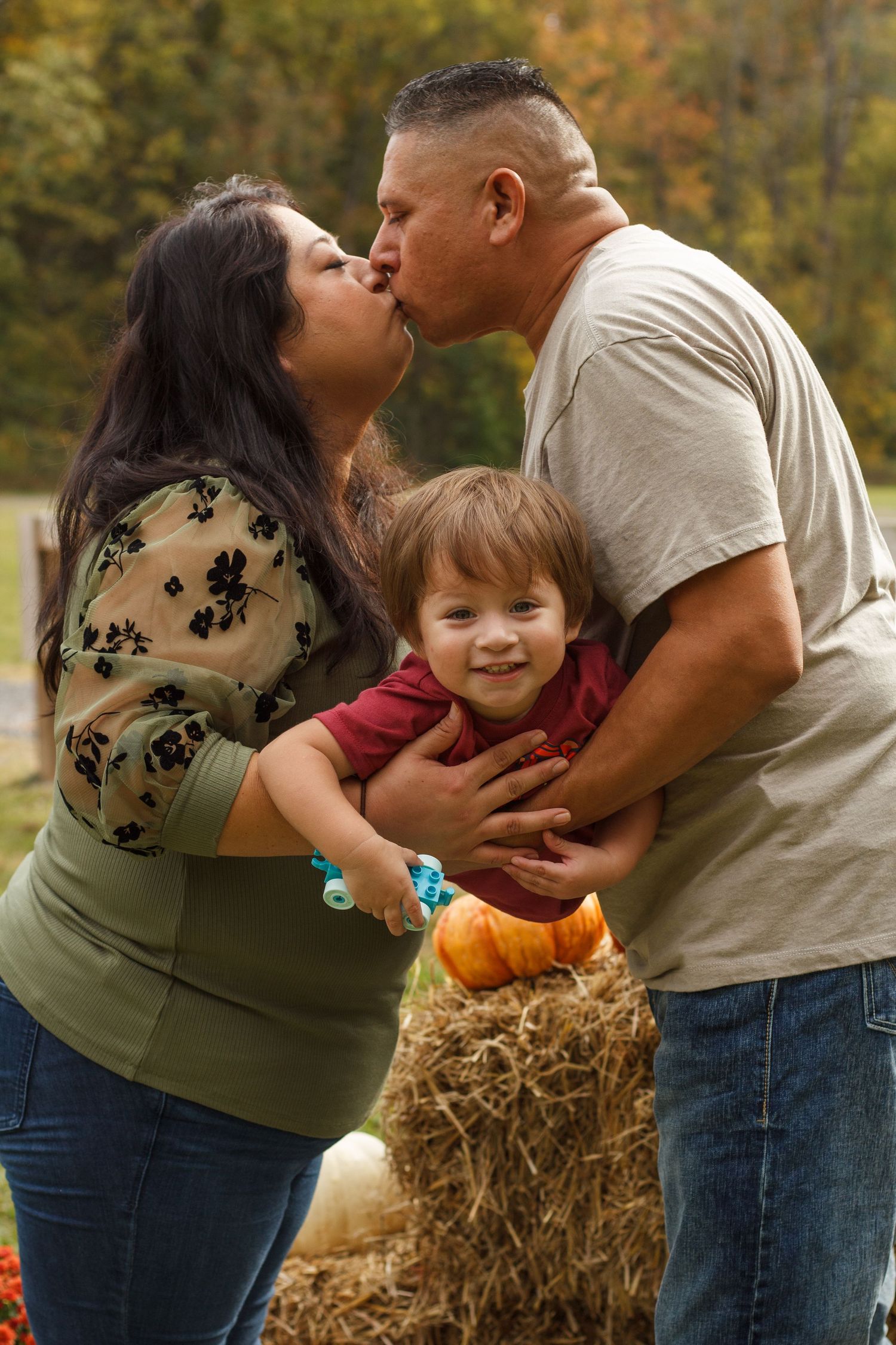 parents kissing while swaying toddler in the hair – candid family photography in Chatsworth GA.