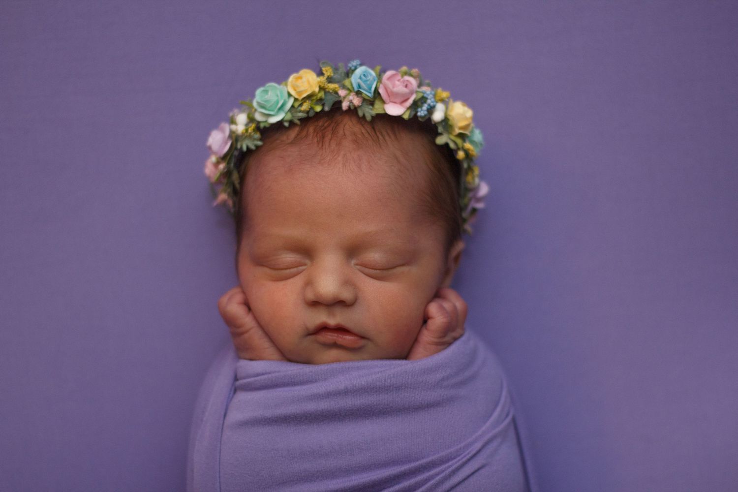 Close-up of sleeping newborn girl in purple wrap and floral crown – Dalton GA newborn session.