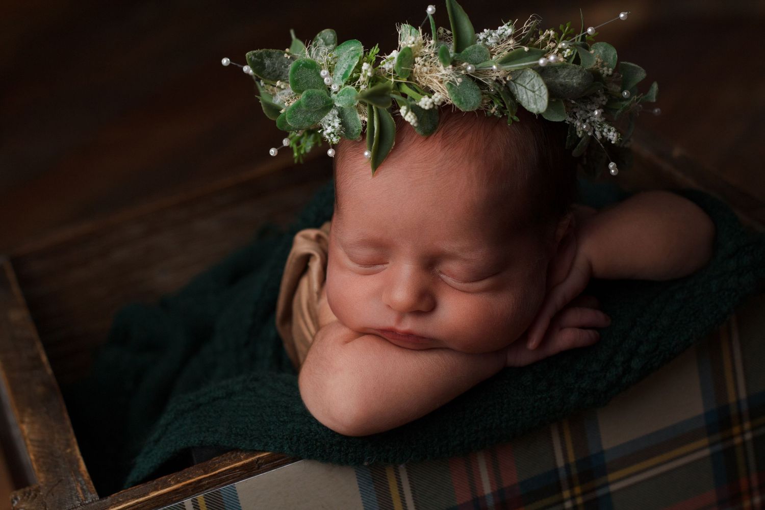 Newborn baby girl wrapped in deep green fabric wearing a greenery halo during a styled newborn photography session in Dalton, Georgia.