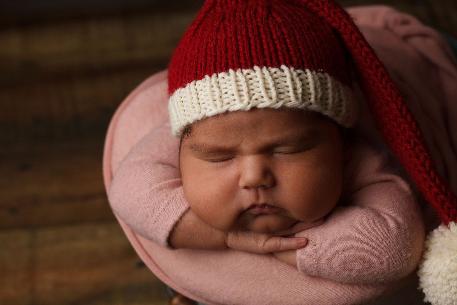 Newborn baby girl sleeping in a red knit hat and pink sleeper during a styled newborn photography session in Dalton, Georgia.