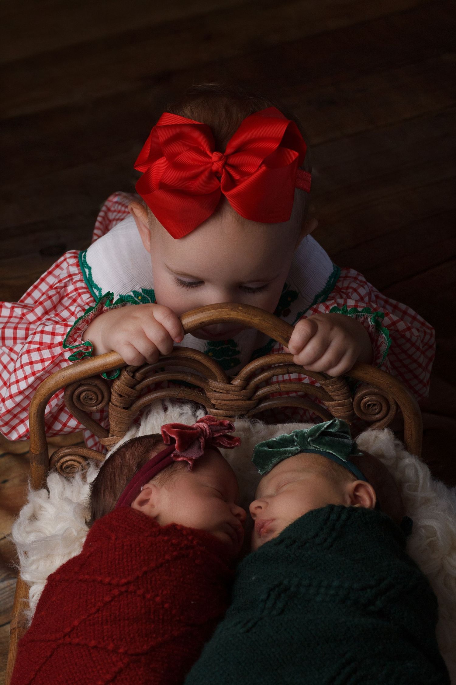 Twin newborn baby girls posed together wearing festive bows  with sibling during a newborn photography session in Dalton, Georgia.