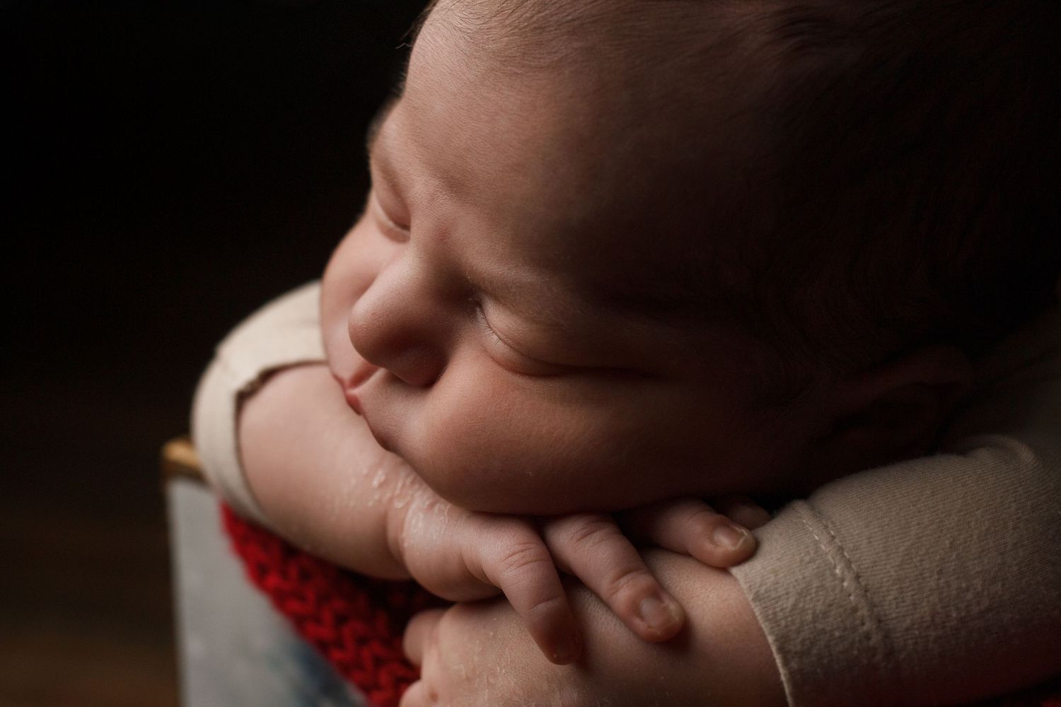 Close-up of a newborn baby sleeping with hands tucked under chin during a newborn photography session in Dalton, Georgia.