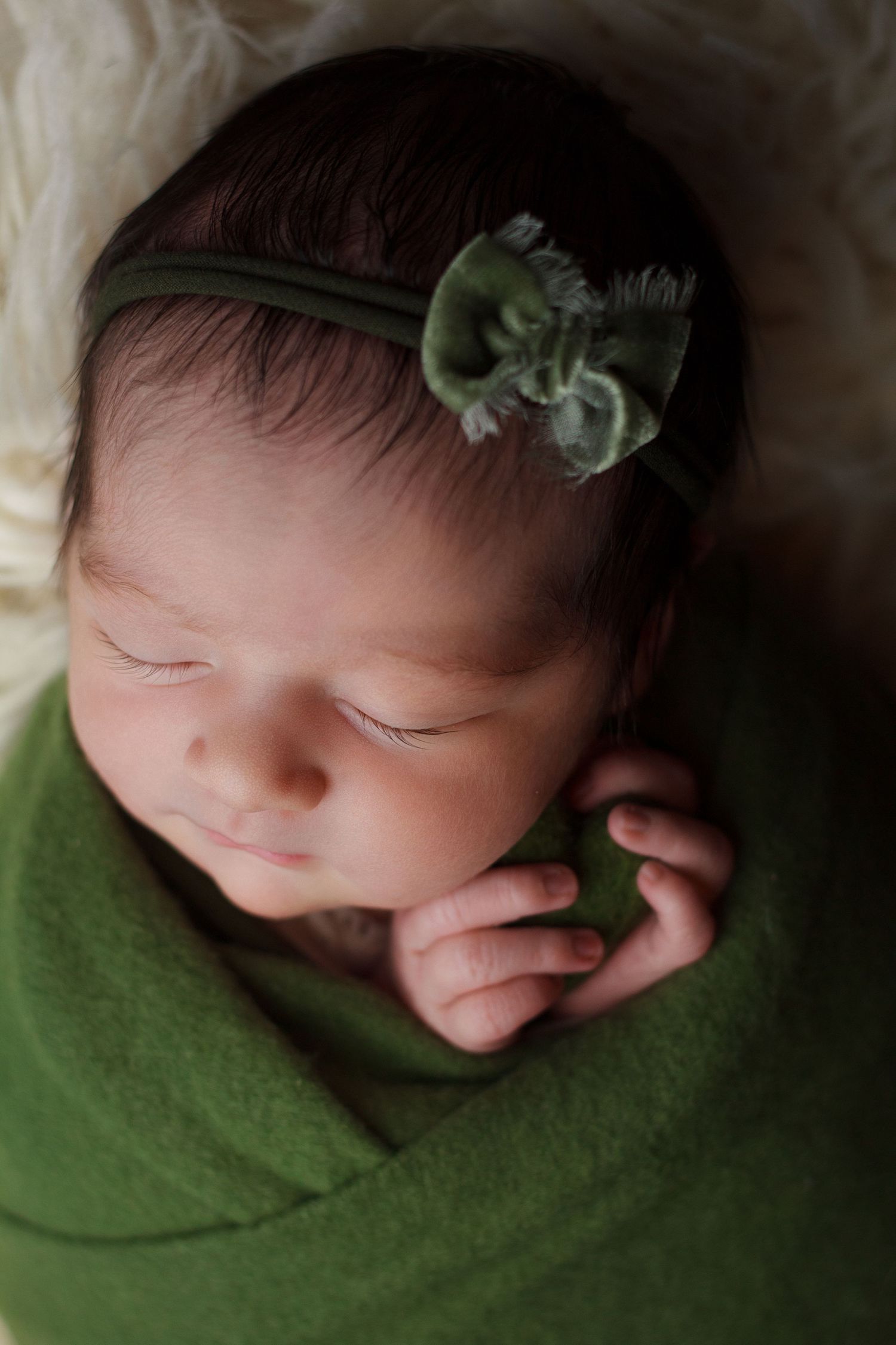Sleeping newborn wrapped in green with a delicate headband during a studio newborn photography session in Dalton, Georgia.