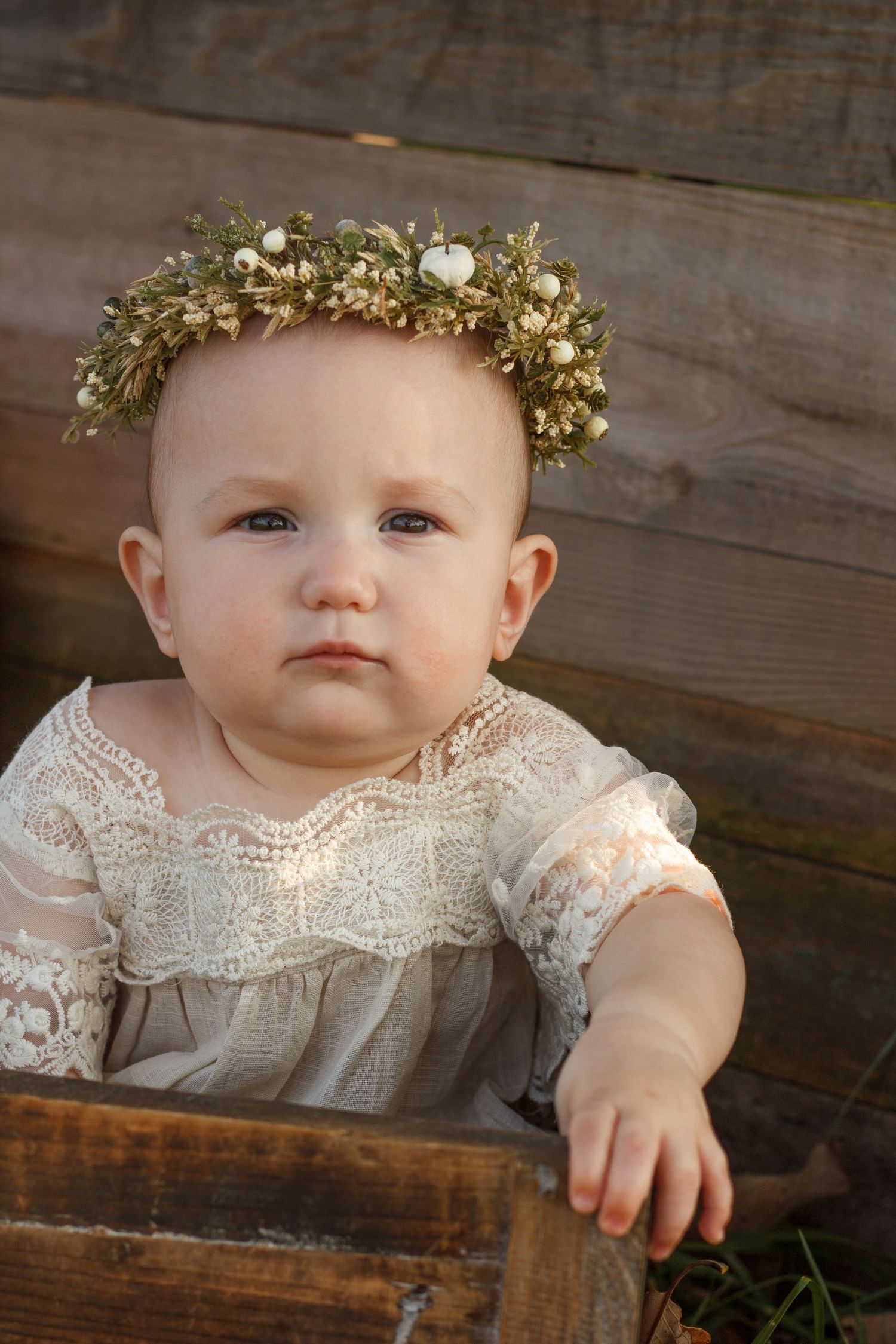 Smiling baby girl in neutral outfit against rustic wooden backdrop – children’s portraits in Tunnel Hill GA.