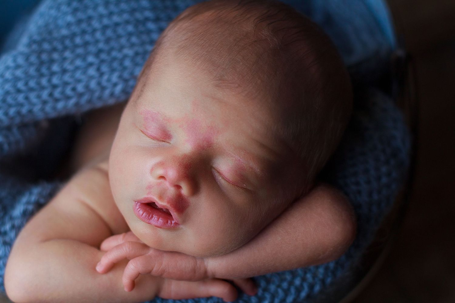 Baby boy resting in a bucket on a blue knit layer with his head on him hands during a Chatsworth Georgia newborn session