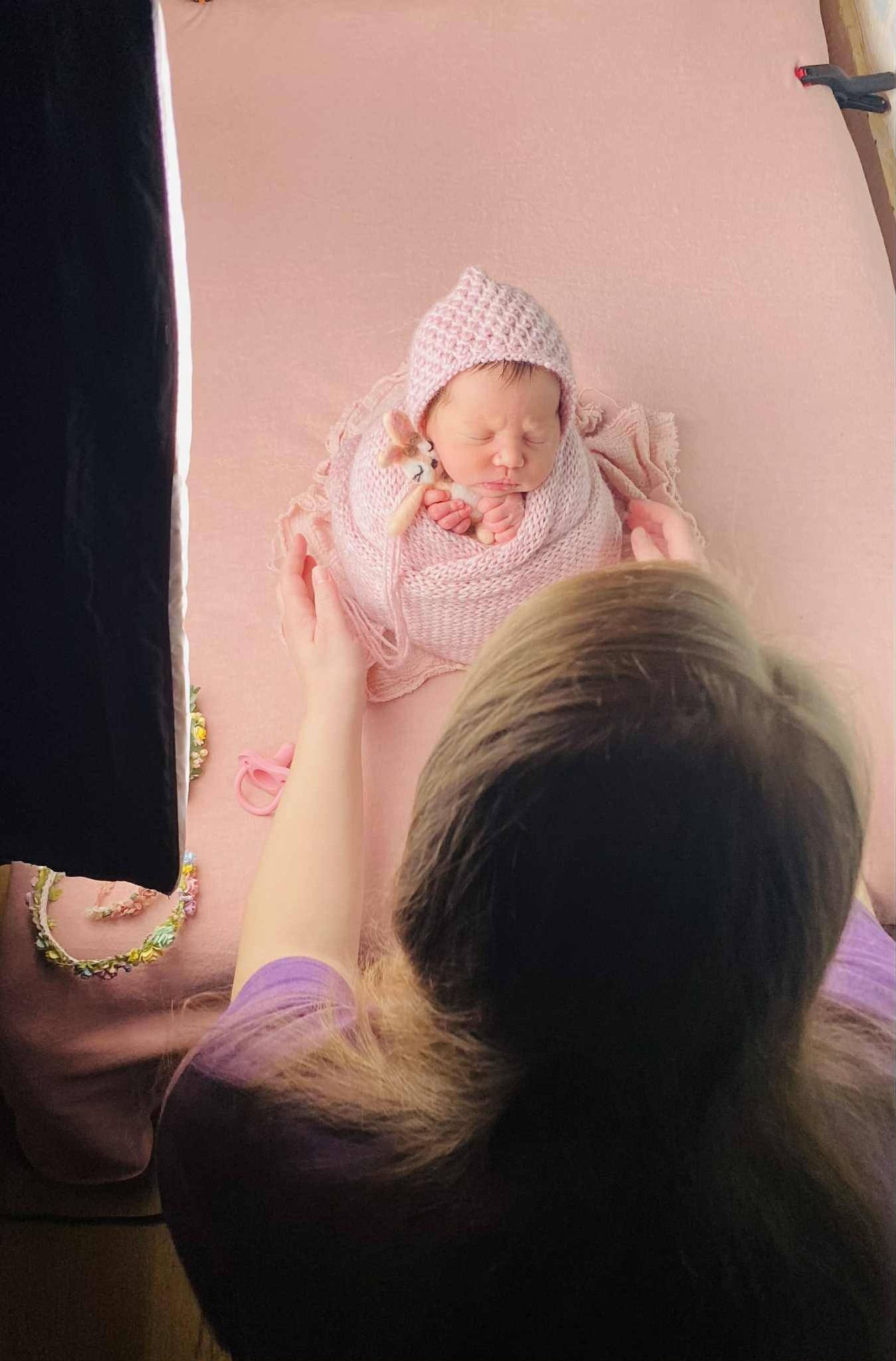 Dalton GA newborn photographer Tiffany capturing a cozy in-home session with a baby wrapped in a soft pink knit wrap.