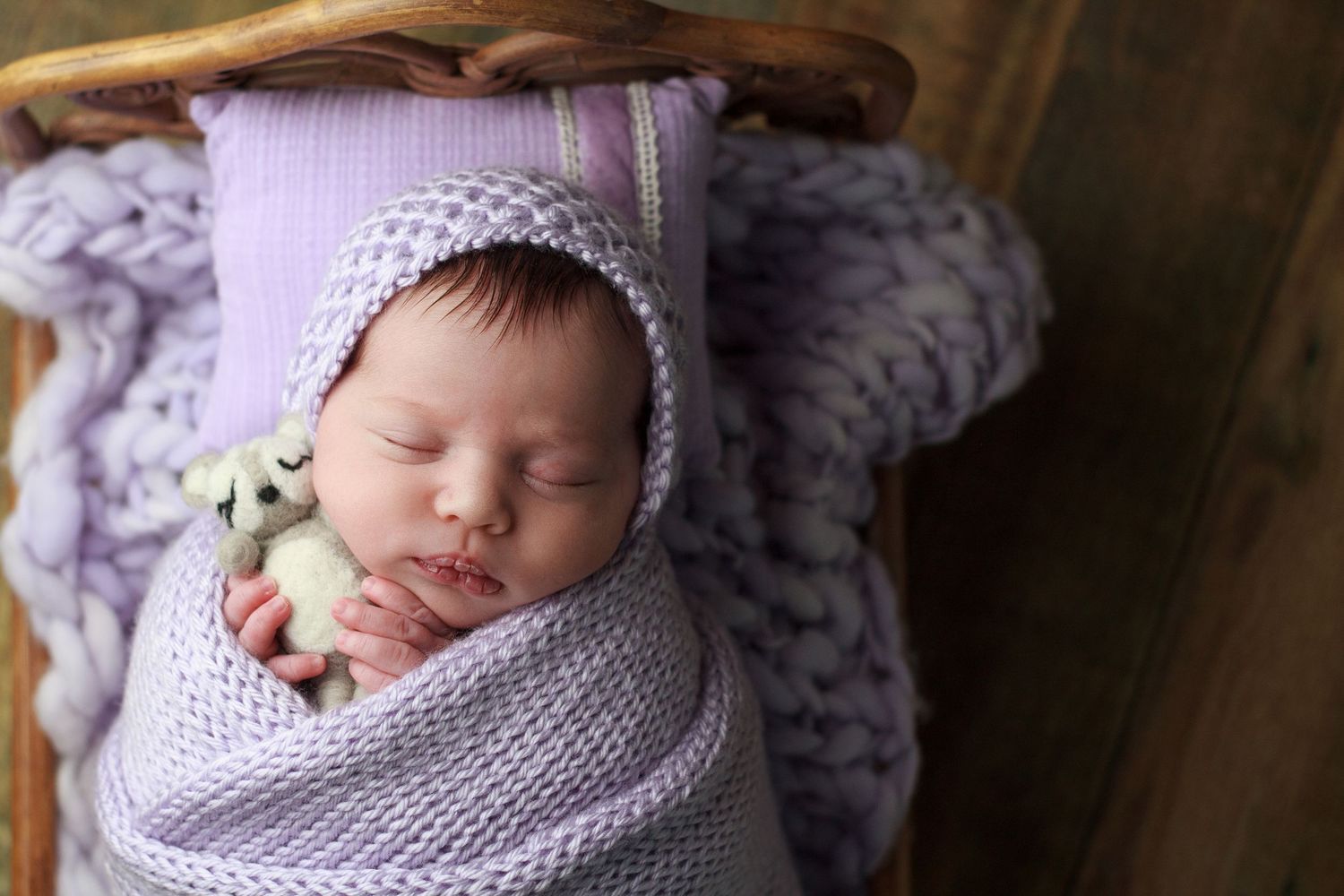 Newborn baby wrapped in soft layers on a tiny bed during in‑home session in Dalton GA
