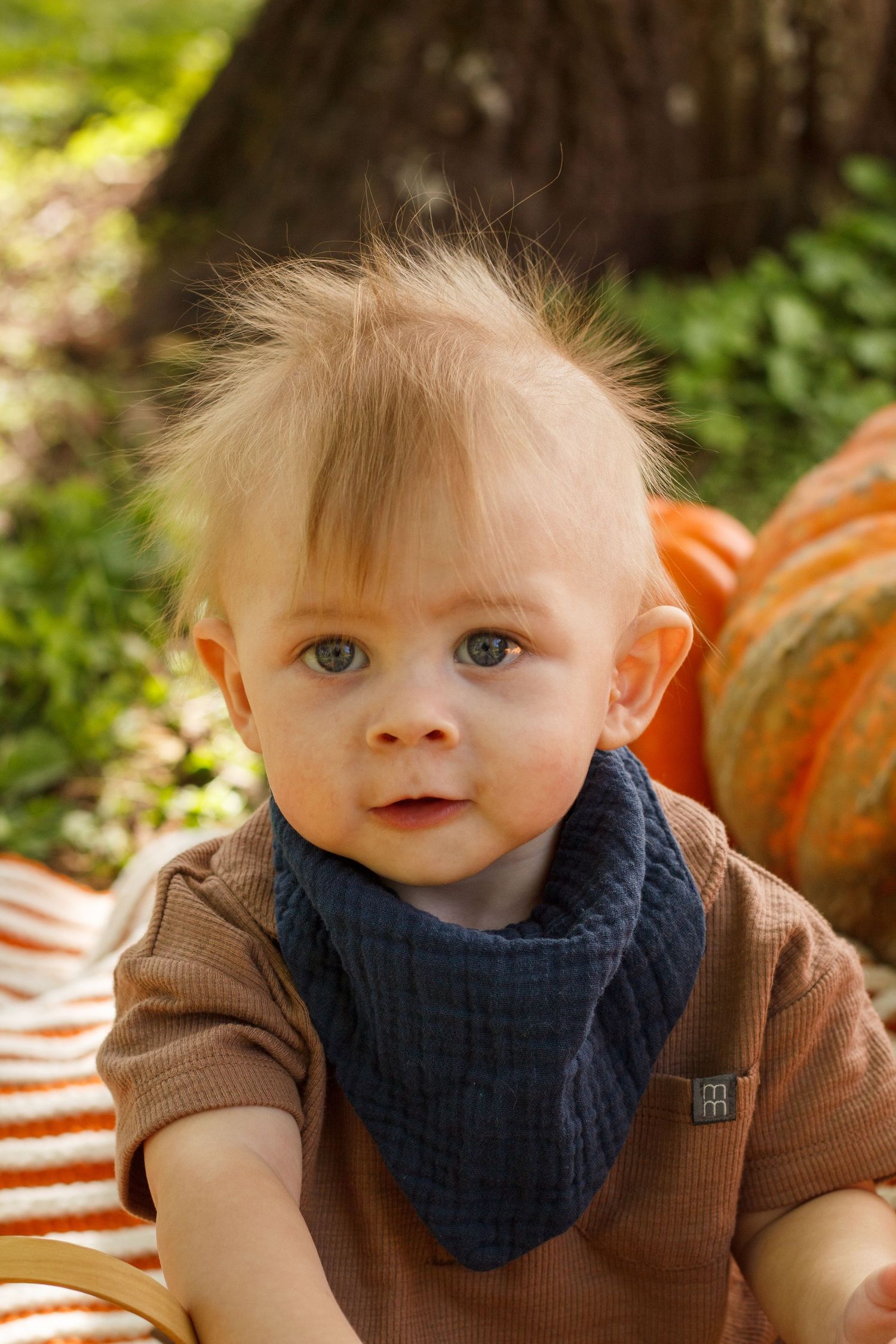 Baby boy with soft fluffy hair sitting on an orange and white striped blanket surrounded by pumpkins during a Tunnel Hill Georgia milestone
