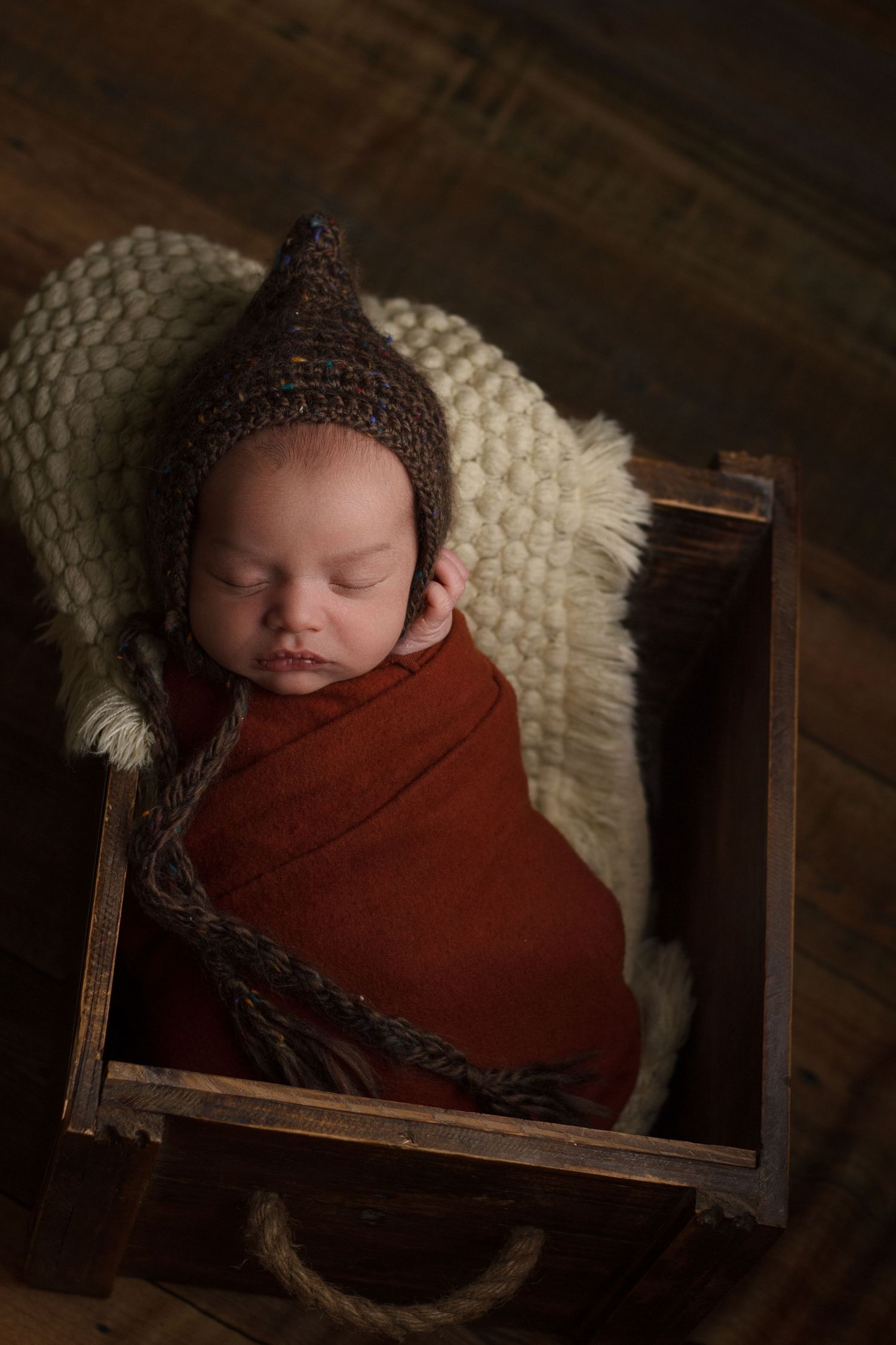 Overhead view of a newborn baby sleeping in a wooden bed during a newborn photography session in Dalton, Georgia.