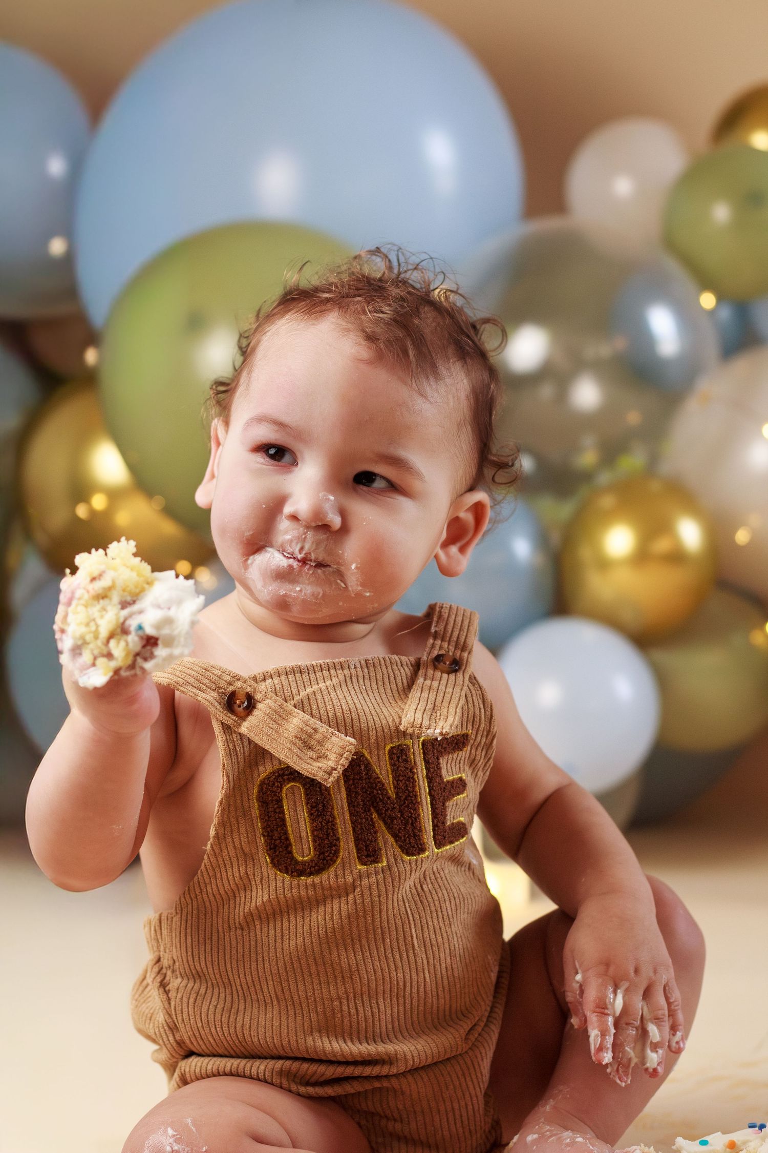 Baby boy with a handful of cake posing during a cake smash session