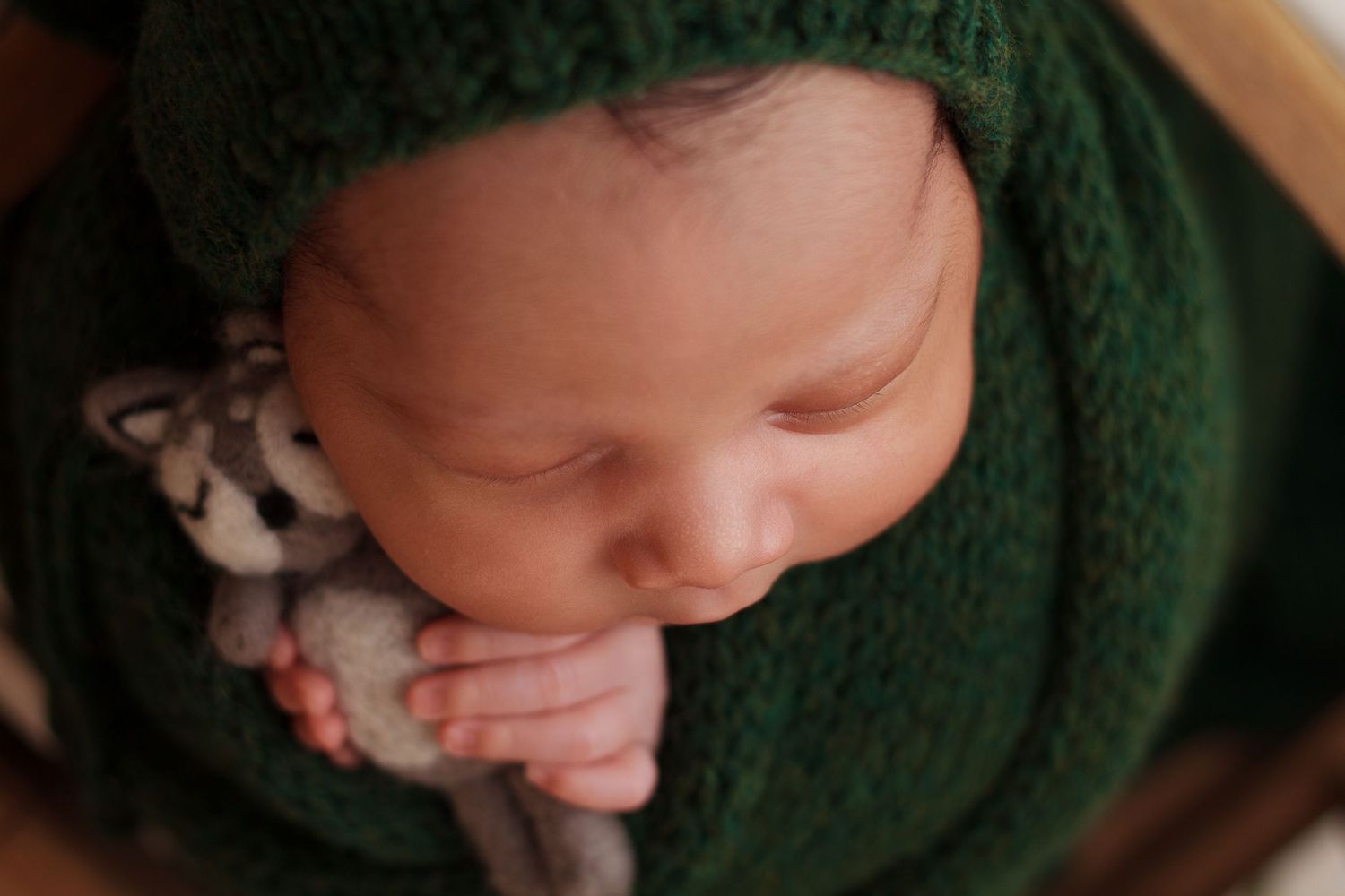 Close up of peaceful newborn baby boy wrapped in dark green, sleeping during in home session in Dalton Georgia