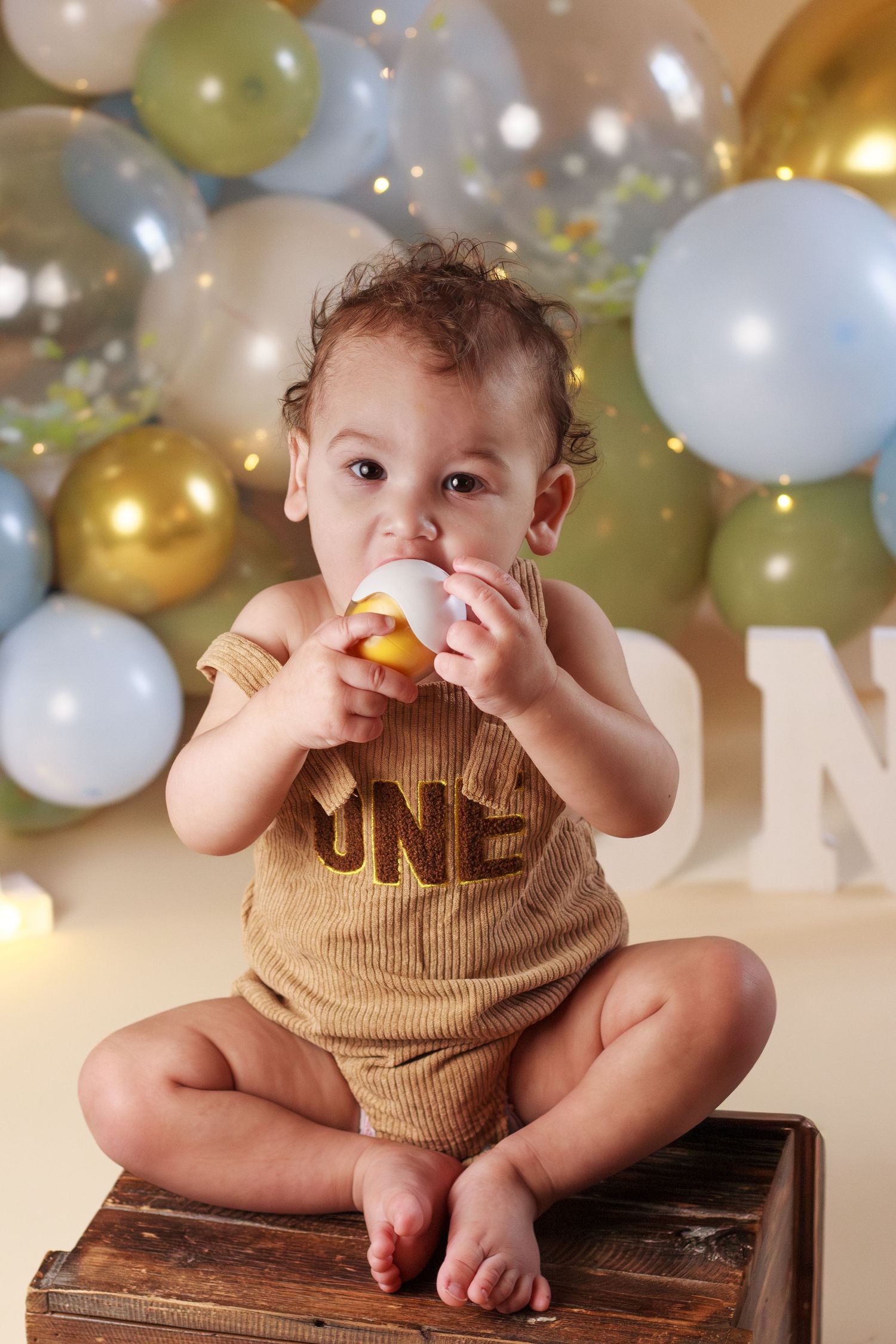 Baby boy chewing on an egg shaped toy while posing during a Dalton Georgia Cake Smash Session