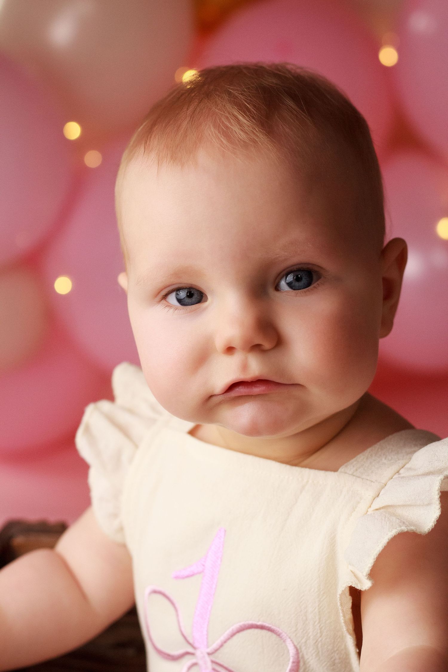 Close up image of baby girl with pink balloons in the background during a Dalton Georgia Cake Smash session
