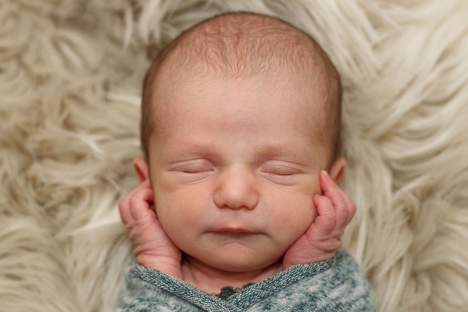 Newborn baby girl sleeping on cream fur rug with hands posed under chin – Dalton Georgia newborn photographer