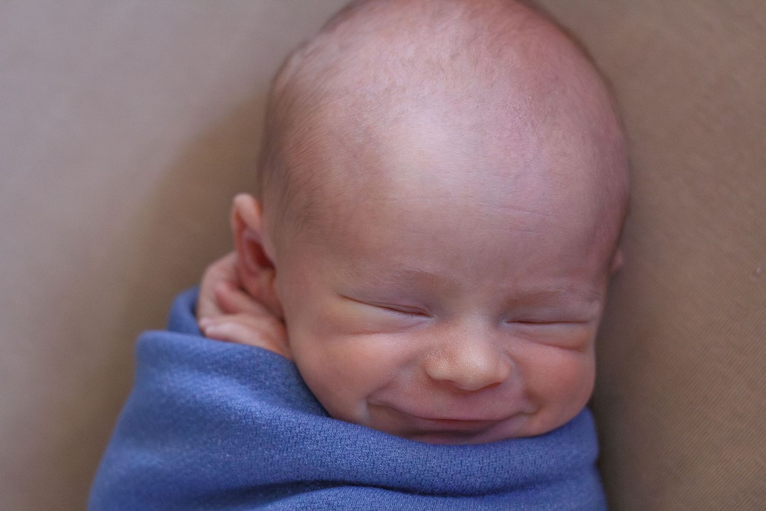 lose-up of sleeping newborn smiling in blue wrap – Chattanooga TN newborn session.