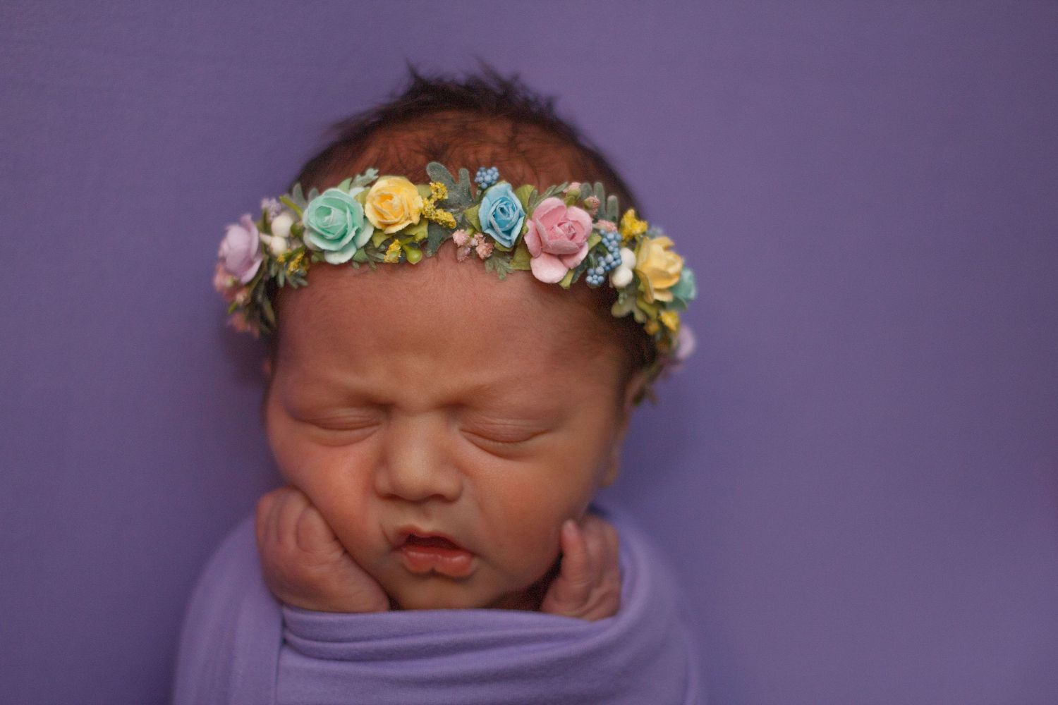Newborn girl in lavender wrap with floral crown, yawning – Chattanooga newborn photographer.