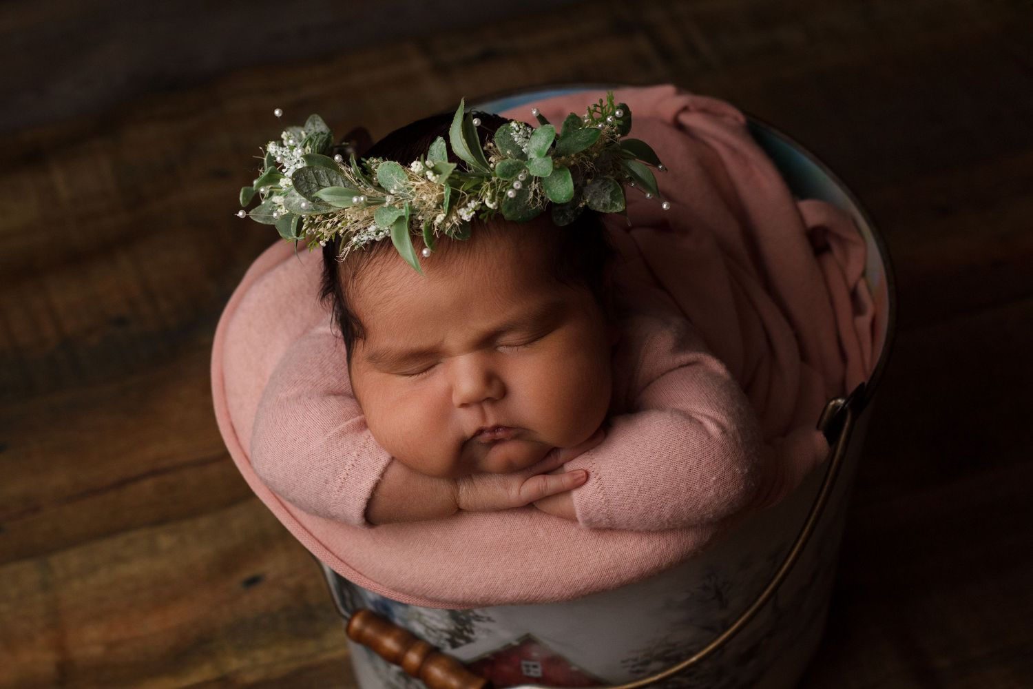 Newborn baby girl wrapped in soft pink fabric wearing a delicate floral crown during a newborn photography session in Dalton, Georgia.