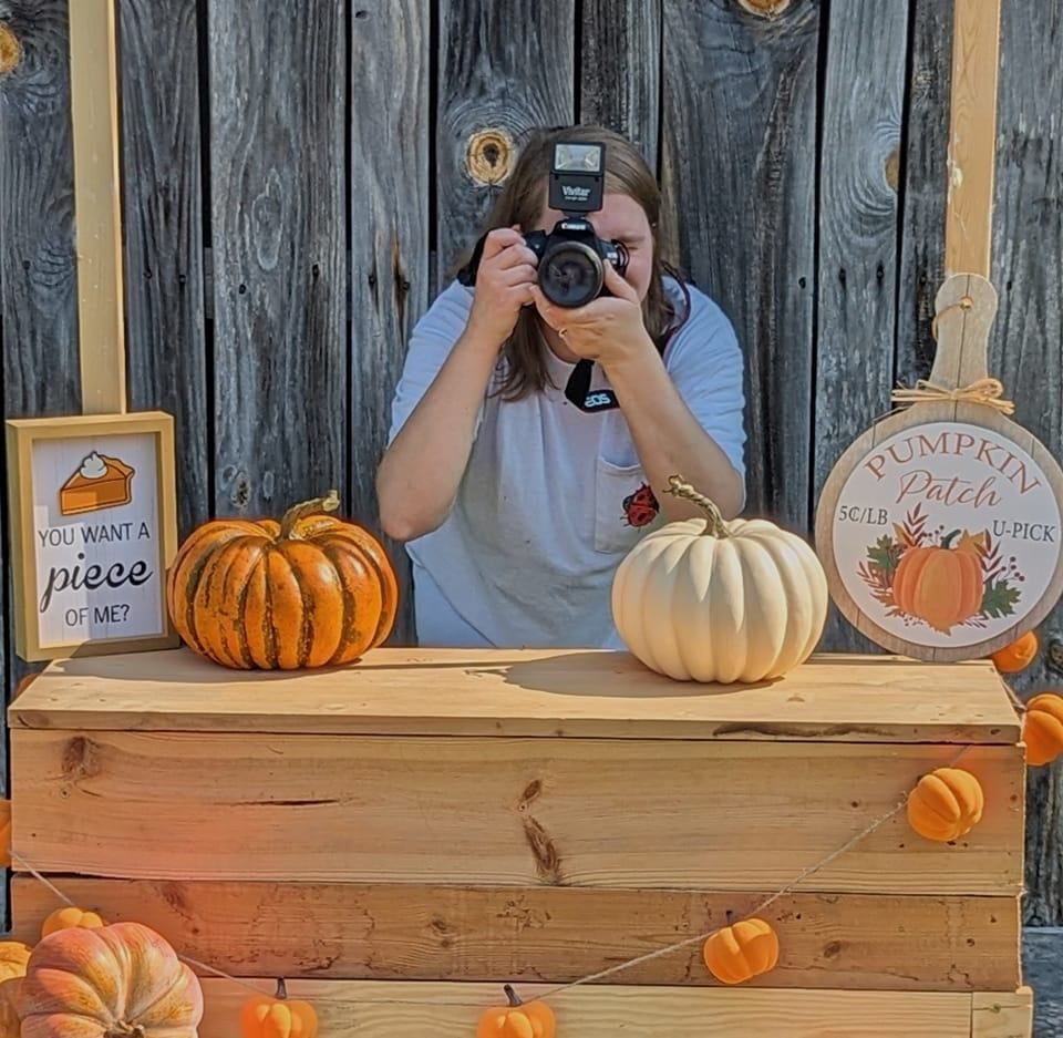 Dalton photographer Tiffany taking a picture from behind her pumpkin stand during a fall mini session