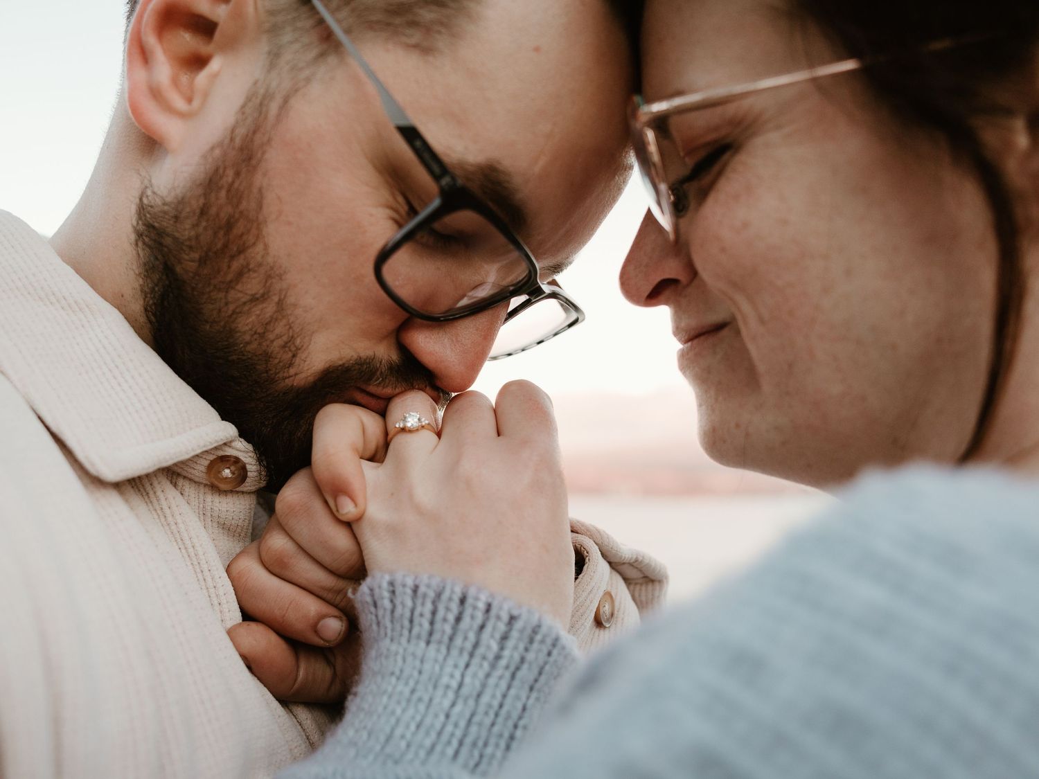 intimate engagement session in west kelowna bc with couple sharing a quiet kiss while admiring her engagement ring