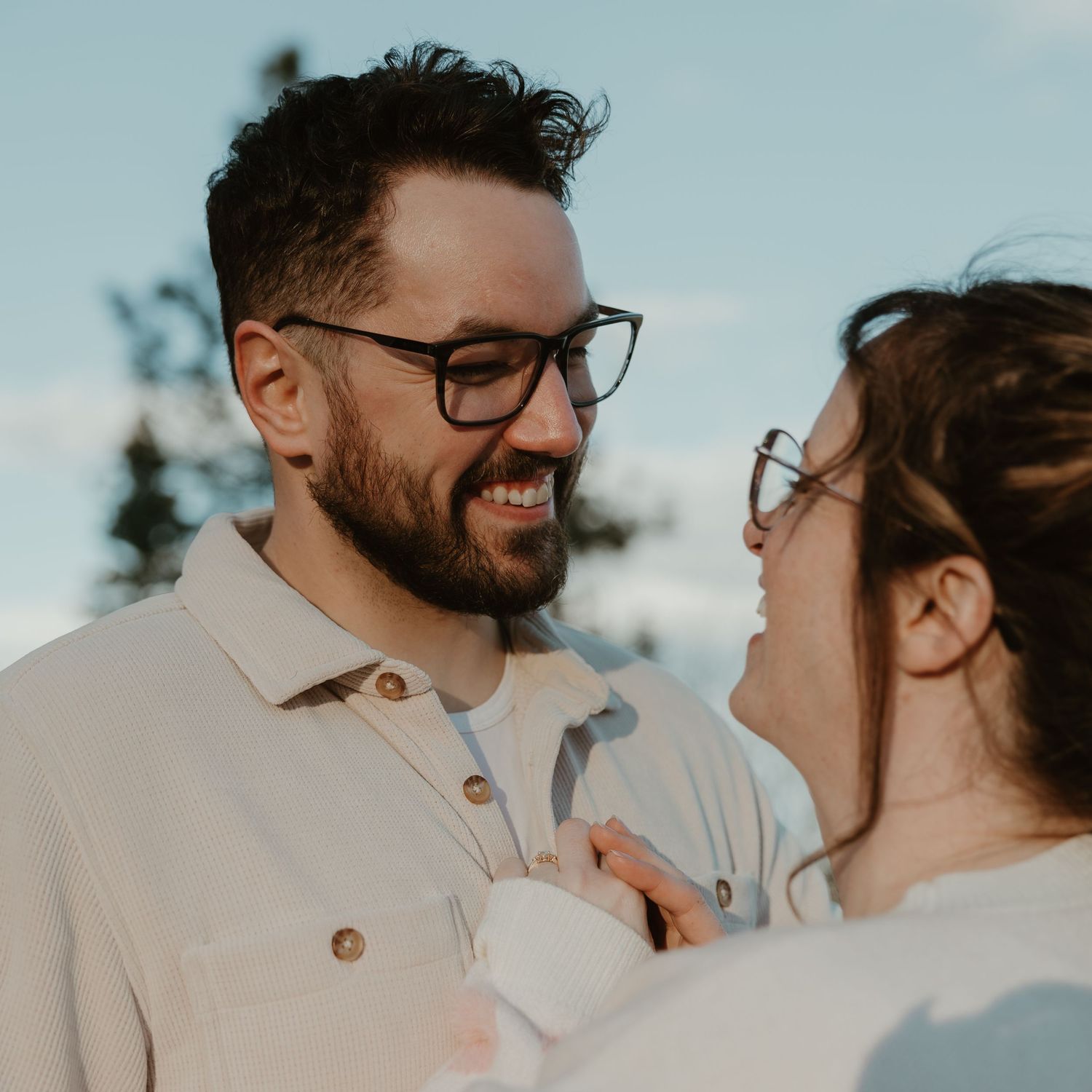 natural engagement photography in the okanagan capturing couple laughing and smiling at each other by okangan lake