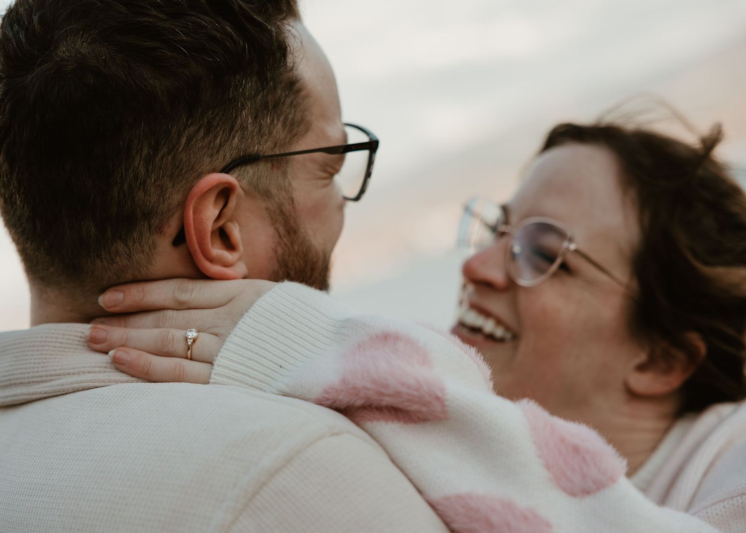 candid engagement photo of couple laughing and smiling during their kelowna engagement session by the lake