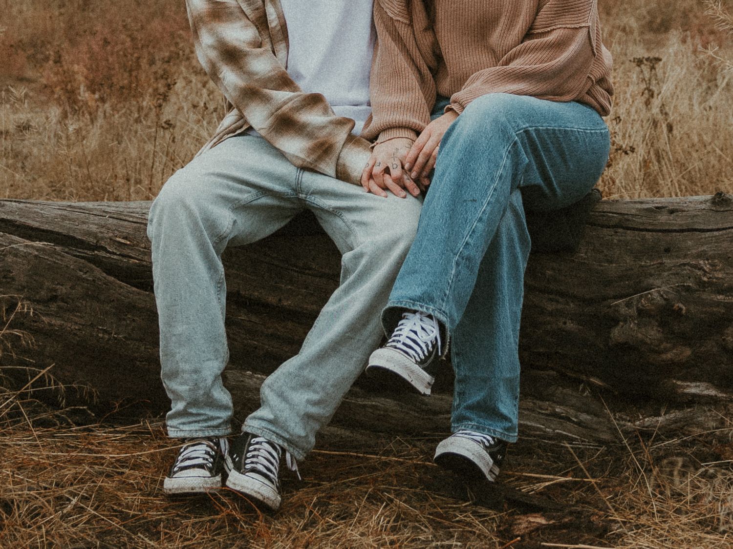 close up details of couple sitting on a log in a grassy field at mission creek park bc