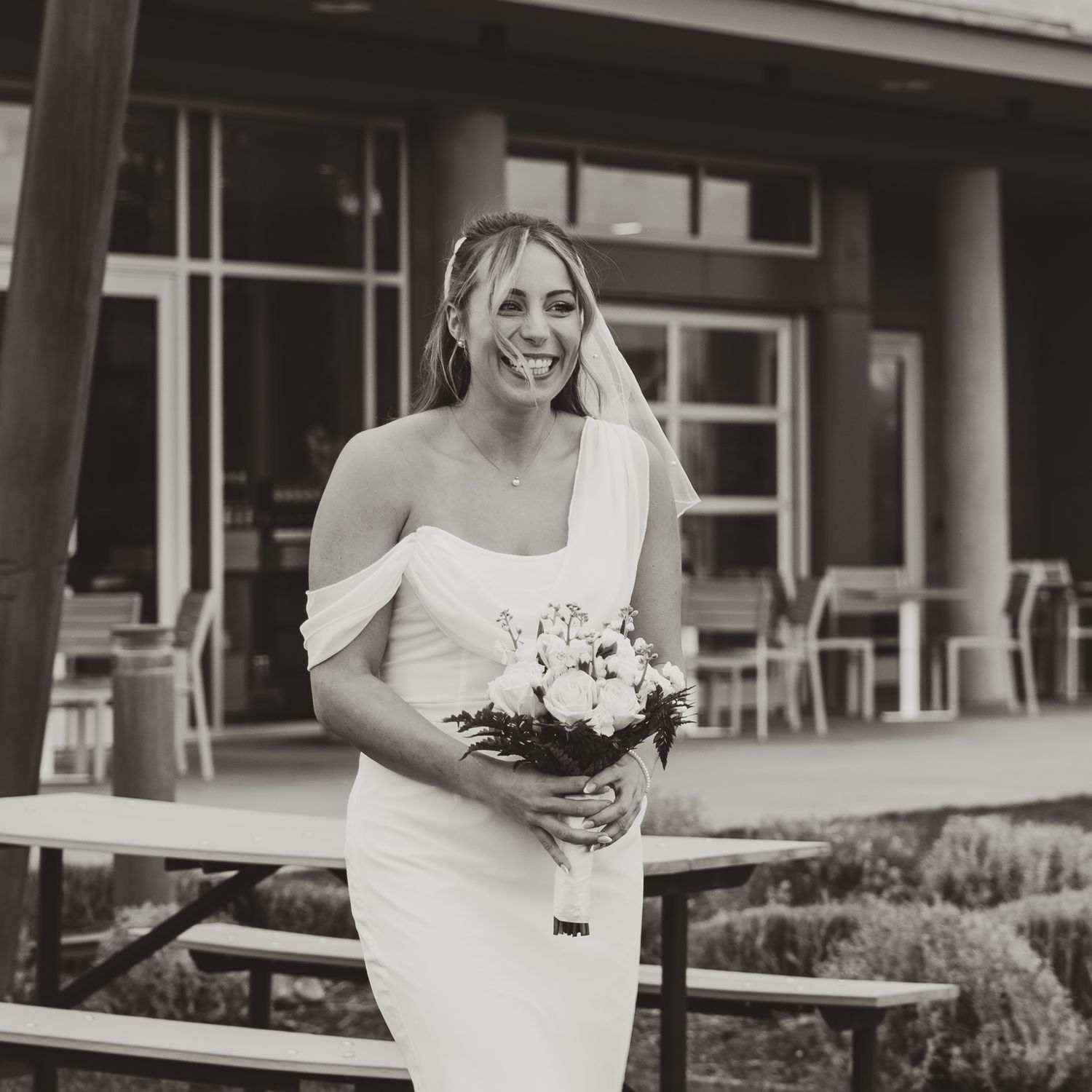 Candid black and white documentary image of bride smiling while she walks down the isle at her elopement wedding in west kelowna bc