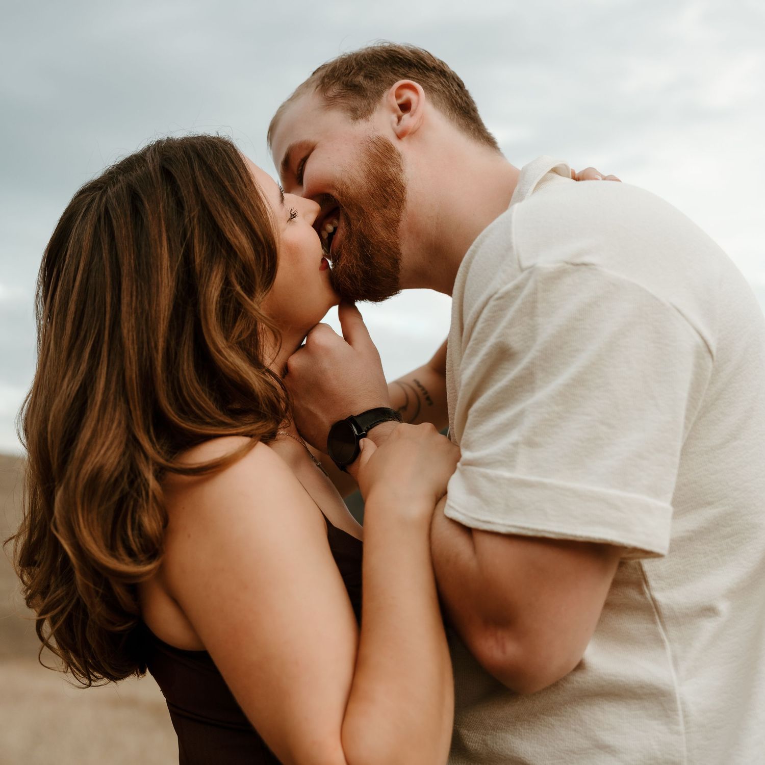 natural engagement photography in Vernon bc capturing couple kissing in field