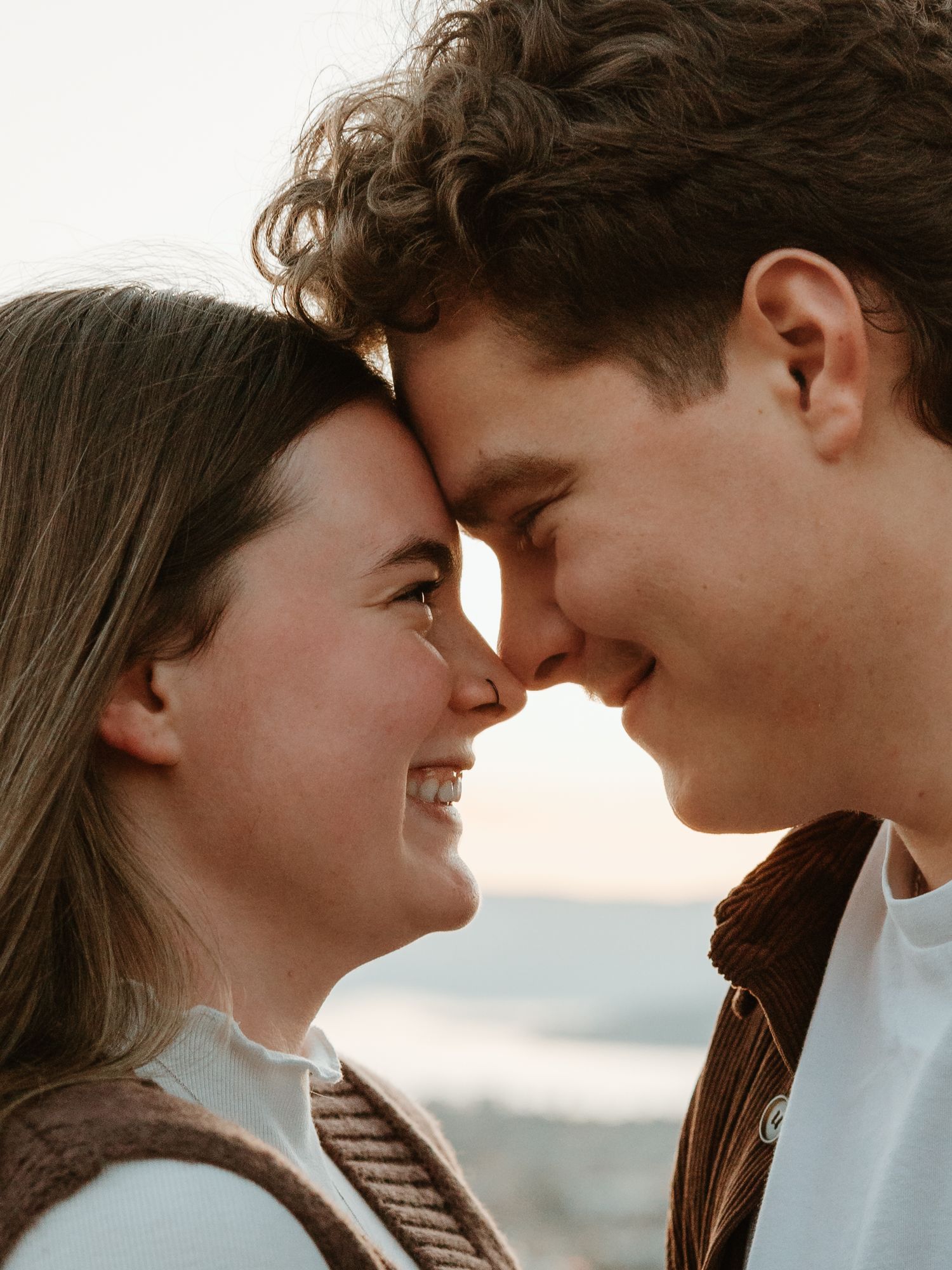 intimate couples photo session in kelowna bc with couple looking into each others eyes at sunset