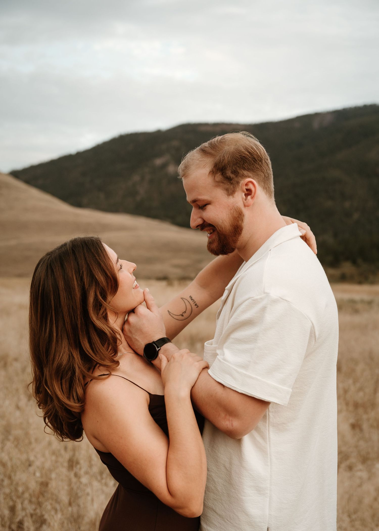 couple smiling at each other during engagement photos at kalamalka lake in Vernon bc