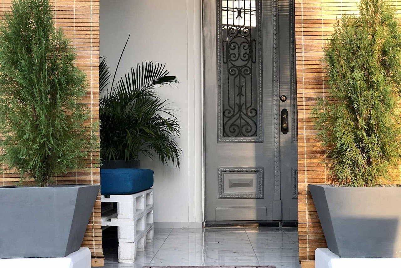 Elegant entrance with ornate white door flanked by potted plants and brick walls.