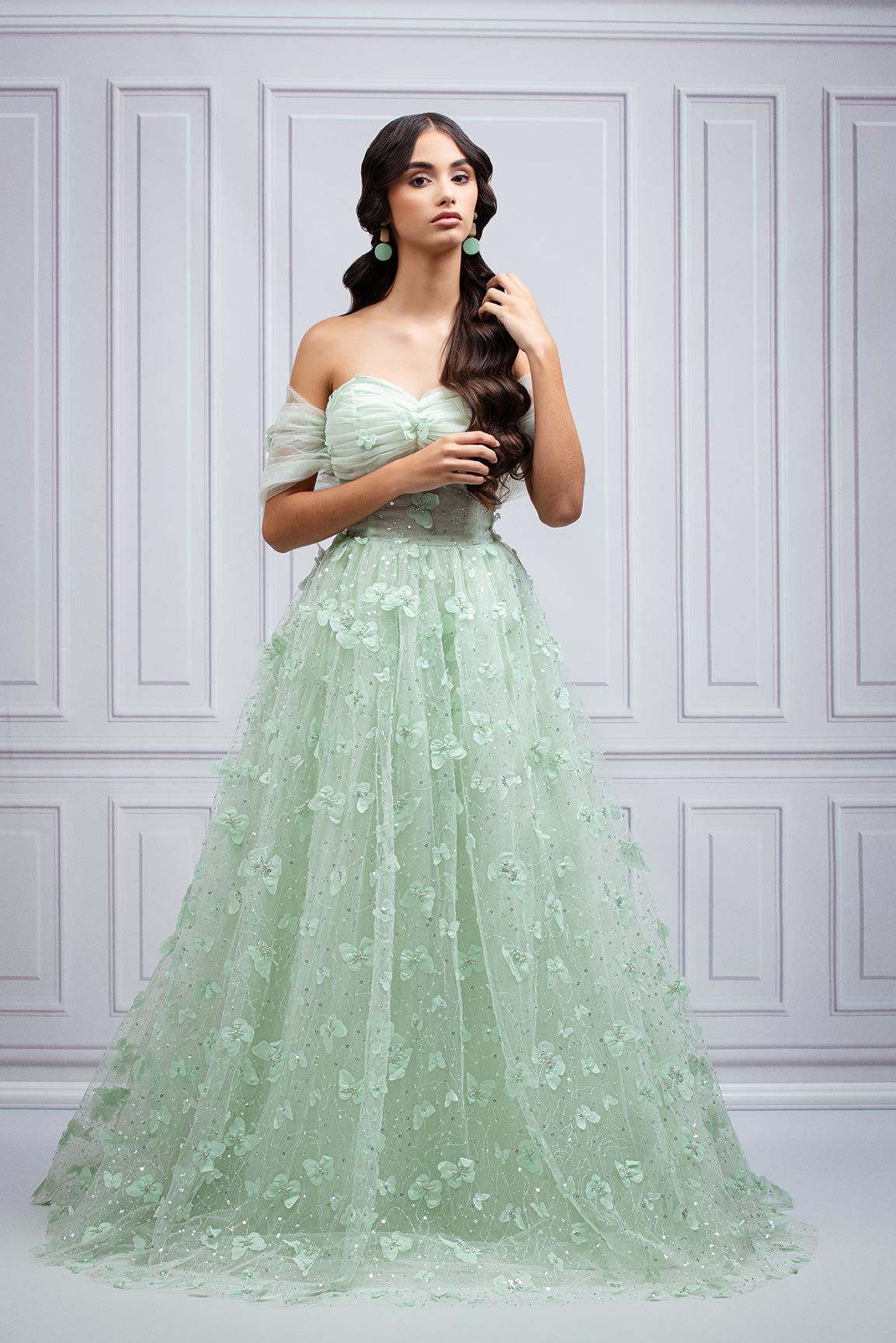 Ethereal mint green tulle ball gown with delicate floral appliques and off-shoulder design in a classic setting.