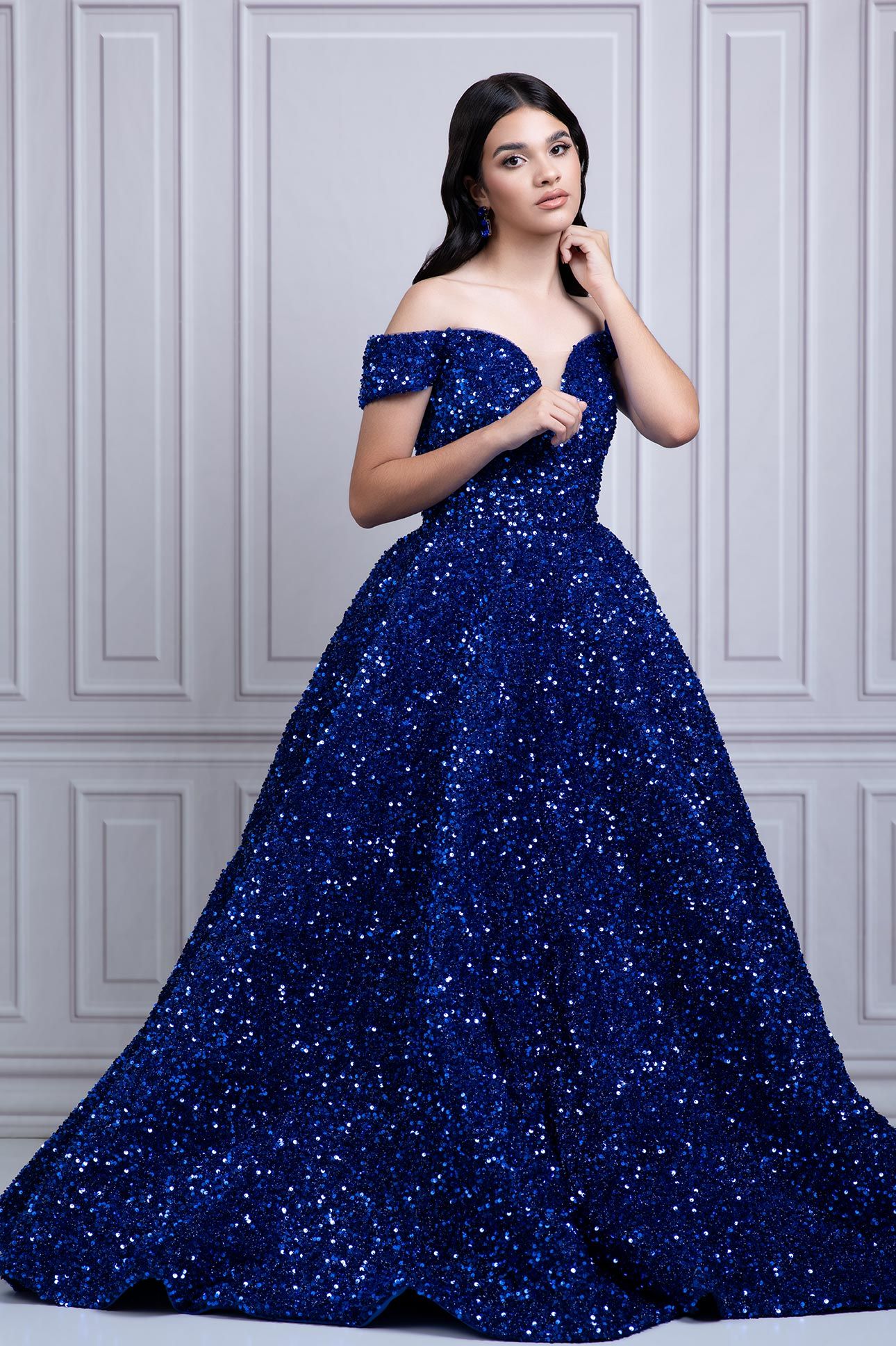 Stunning off-shoulder royal blue sequin ball gown with sweetheart neckline and full princess skirt sparkles in elegant setting.