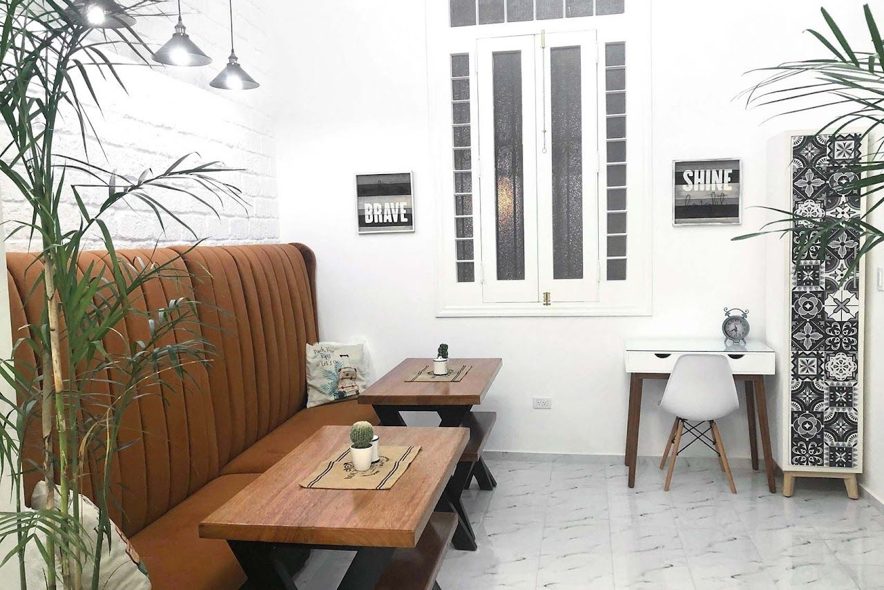 Modern cafe interior with brown leather bench seating, wooden tables, and tropical plants.