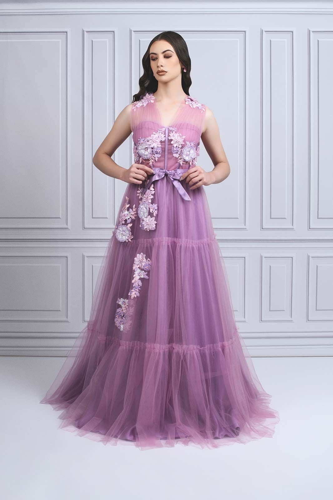 Lavender tulle evening gown with floral appliques and tiered skirt in studio setting.