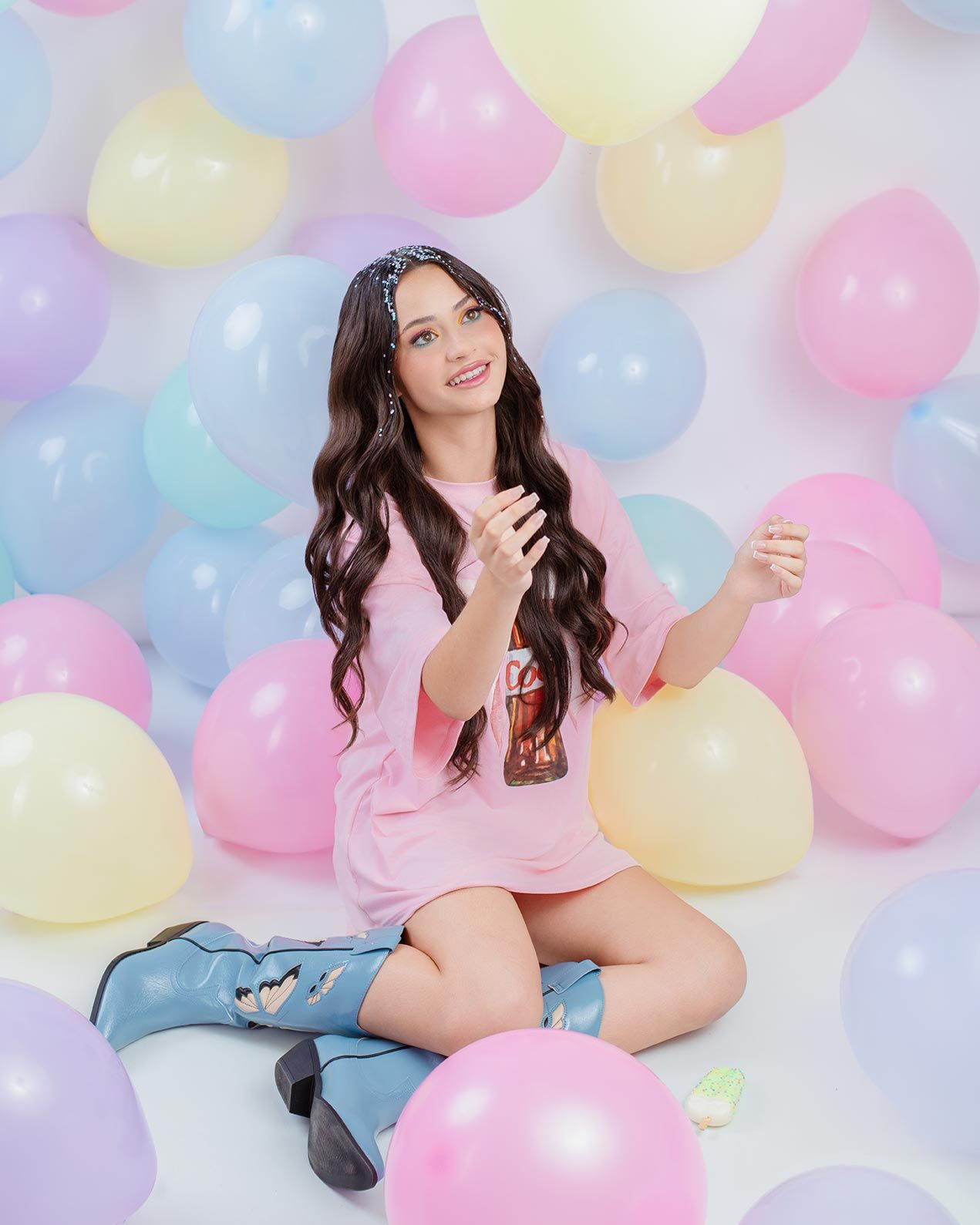 Colorful pastel balloons create dreamy backdrop for shoot with pink shirt and denim outfit.
