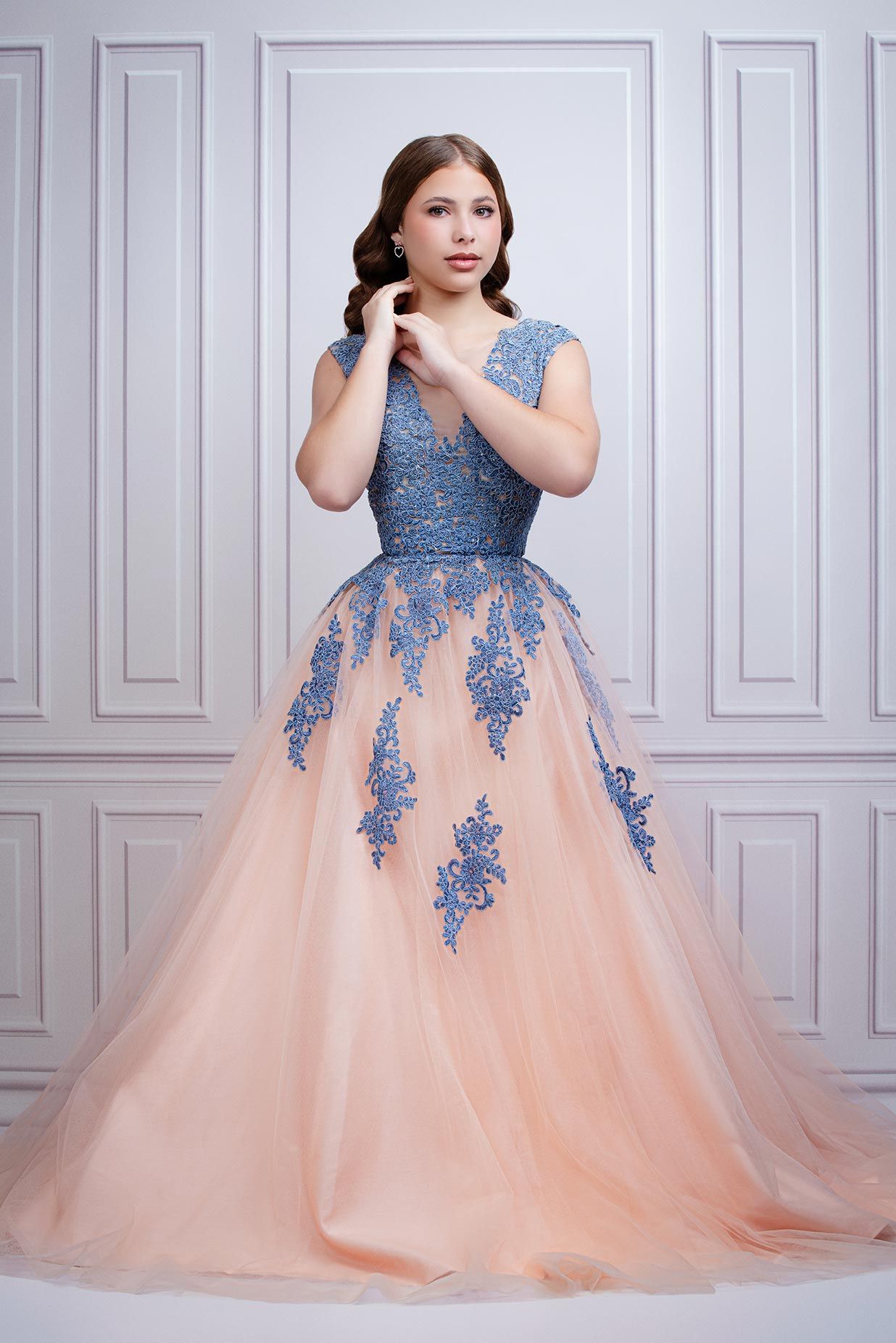 Romantic ball gown featuring peach tulle skirt with blue lace appliques and fitted bodice in classic studio setting.