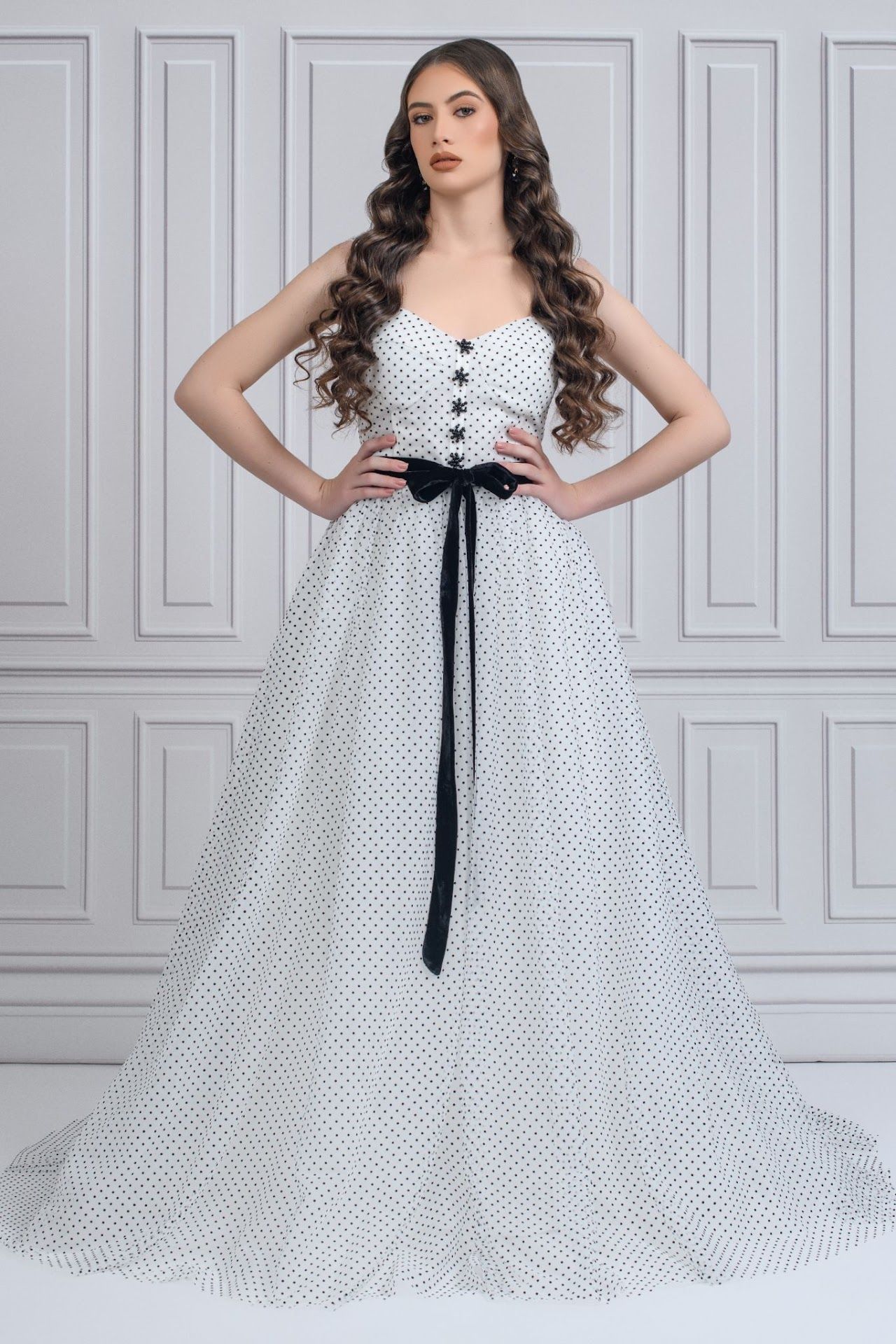 Elegant white polka dot ball gown with black ribbon sash and button-up bodice in classic silhouette.