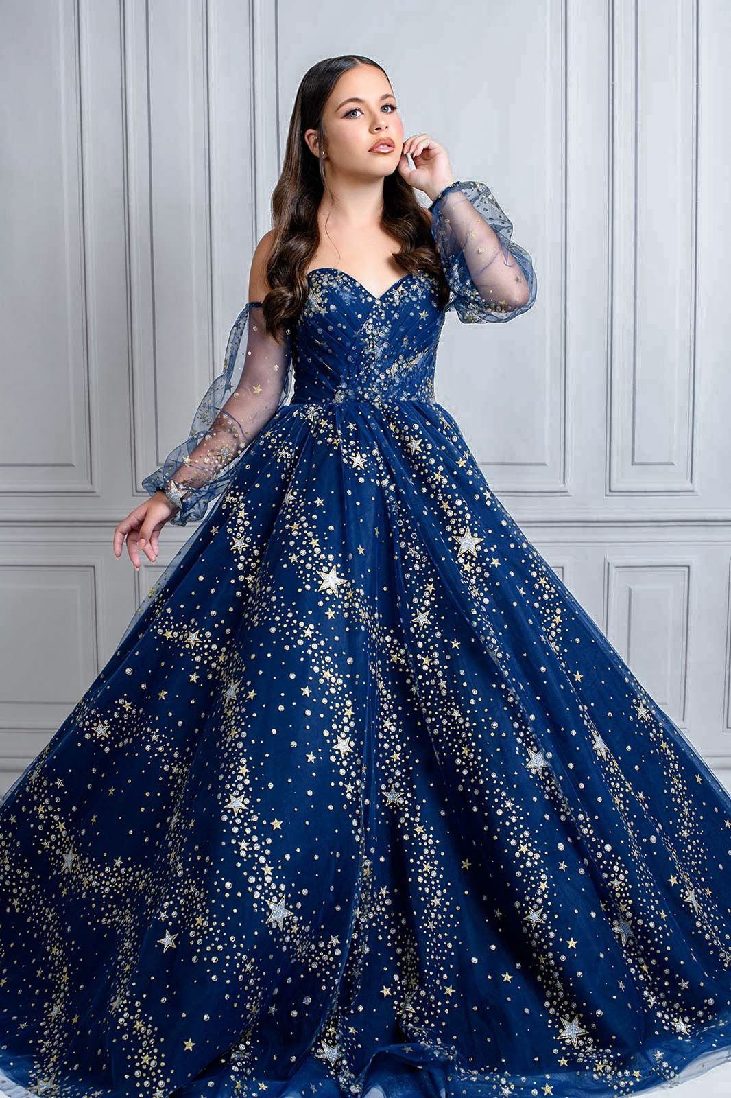 Beautiful evening gown in navy blue tulle with sparkling star pattern and sheer long sleeves creates magical celestial look.